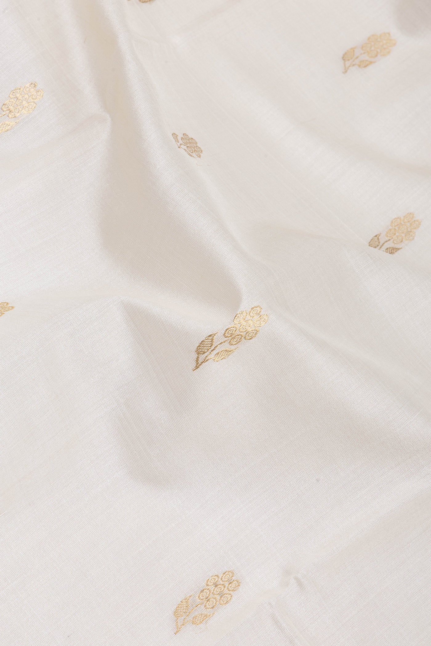 Close up of White Tussar Silk Saree with Zari Butta on the body and Zari Border.  displaying folds