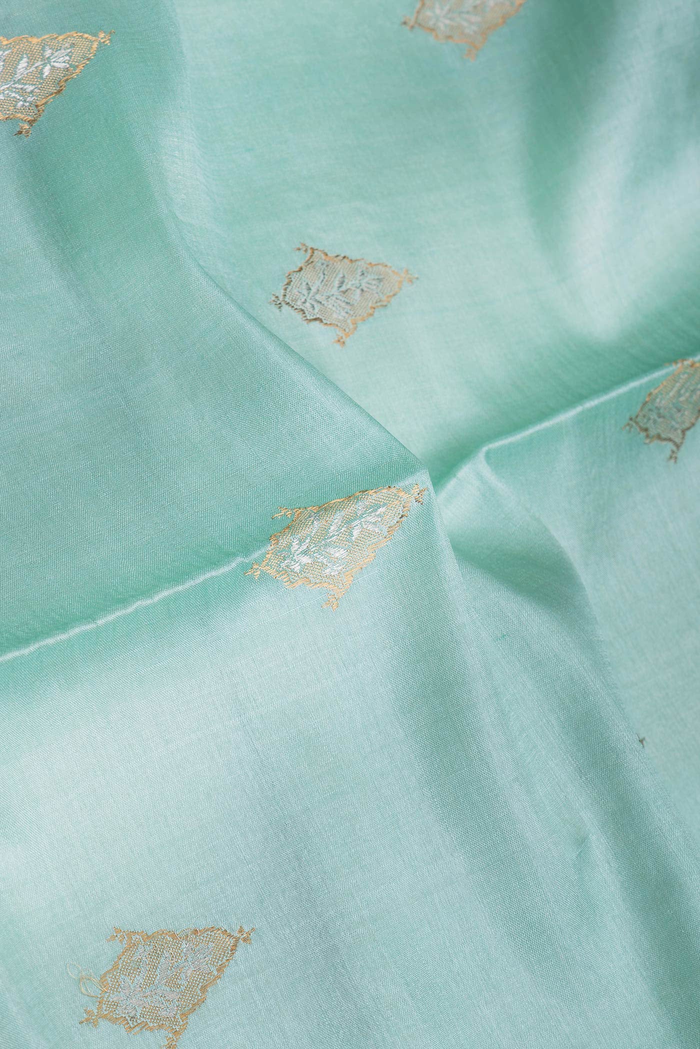 Close up of Sea Green Dual Tone Tussar Silk Saree with Zari Butta on the body and Zari Border.  displaying folds