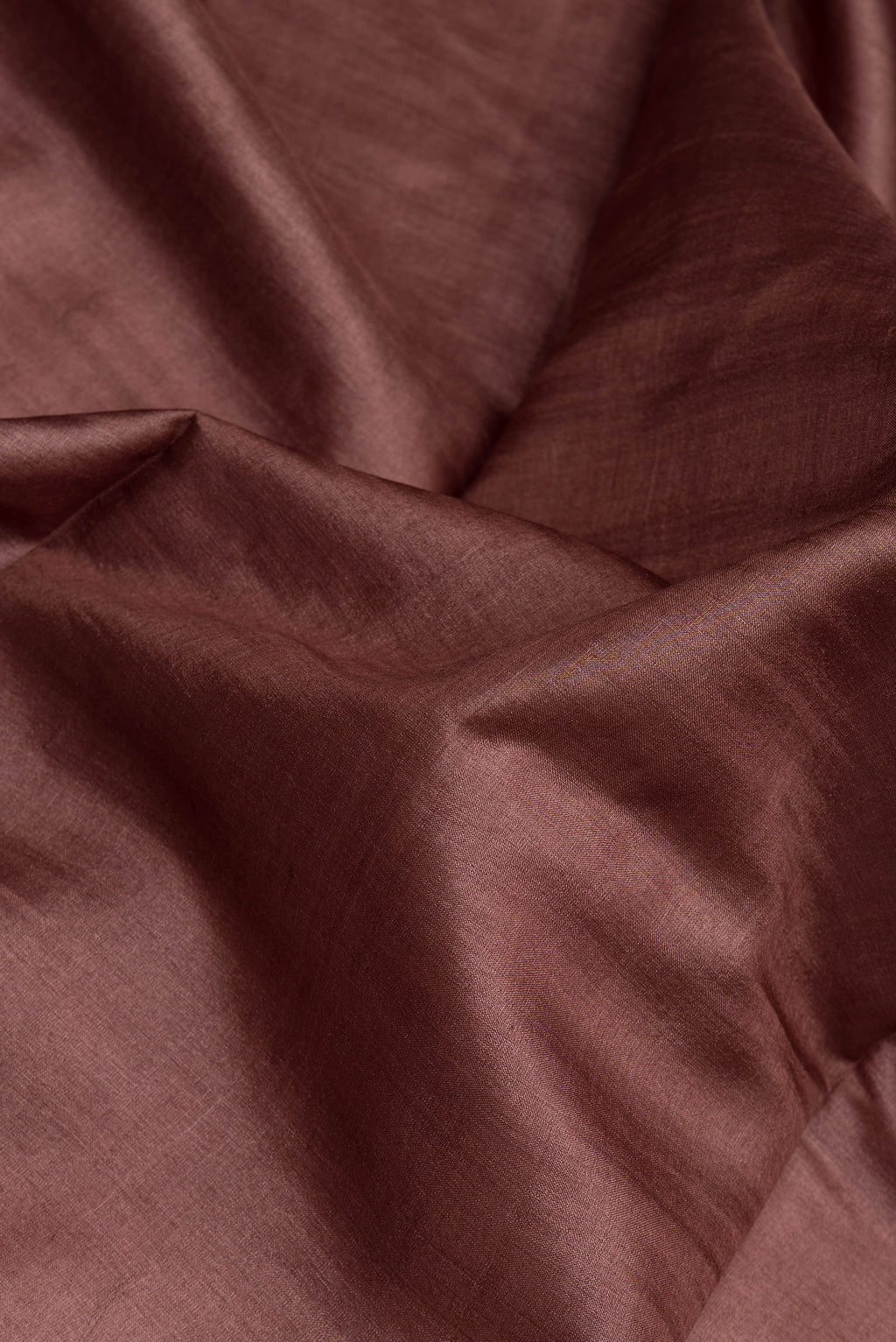 Close up of Brown Tussar Silk Saree with Plain Body and Zari Border.  displaying folds