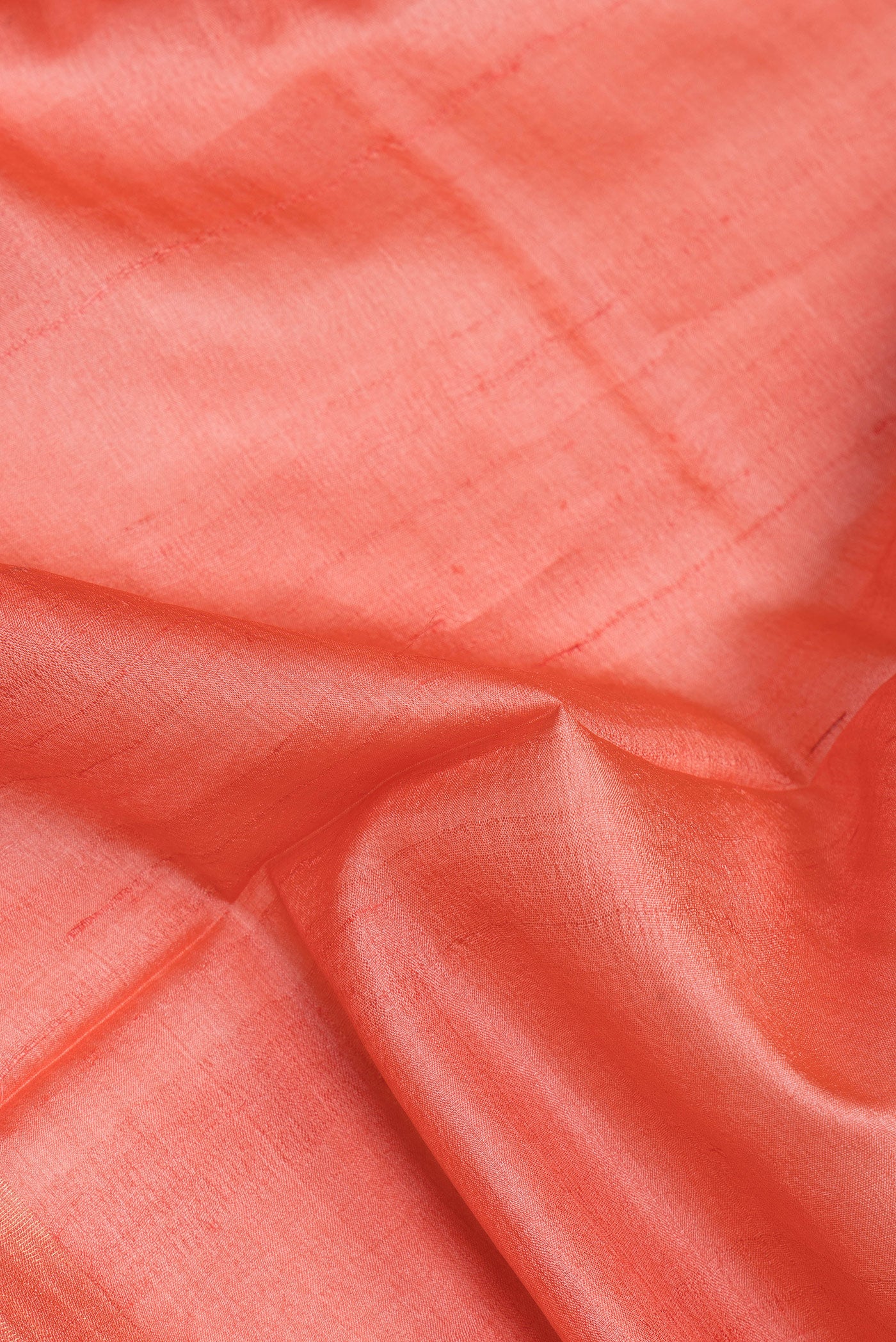 Close up of Peach Tussar Silk Saree with Plain Body and Zari Border.  displaying folds