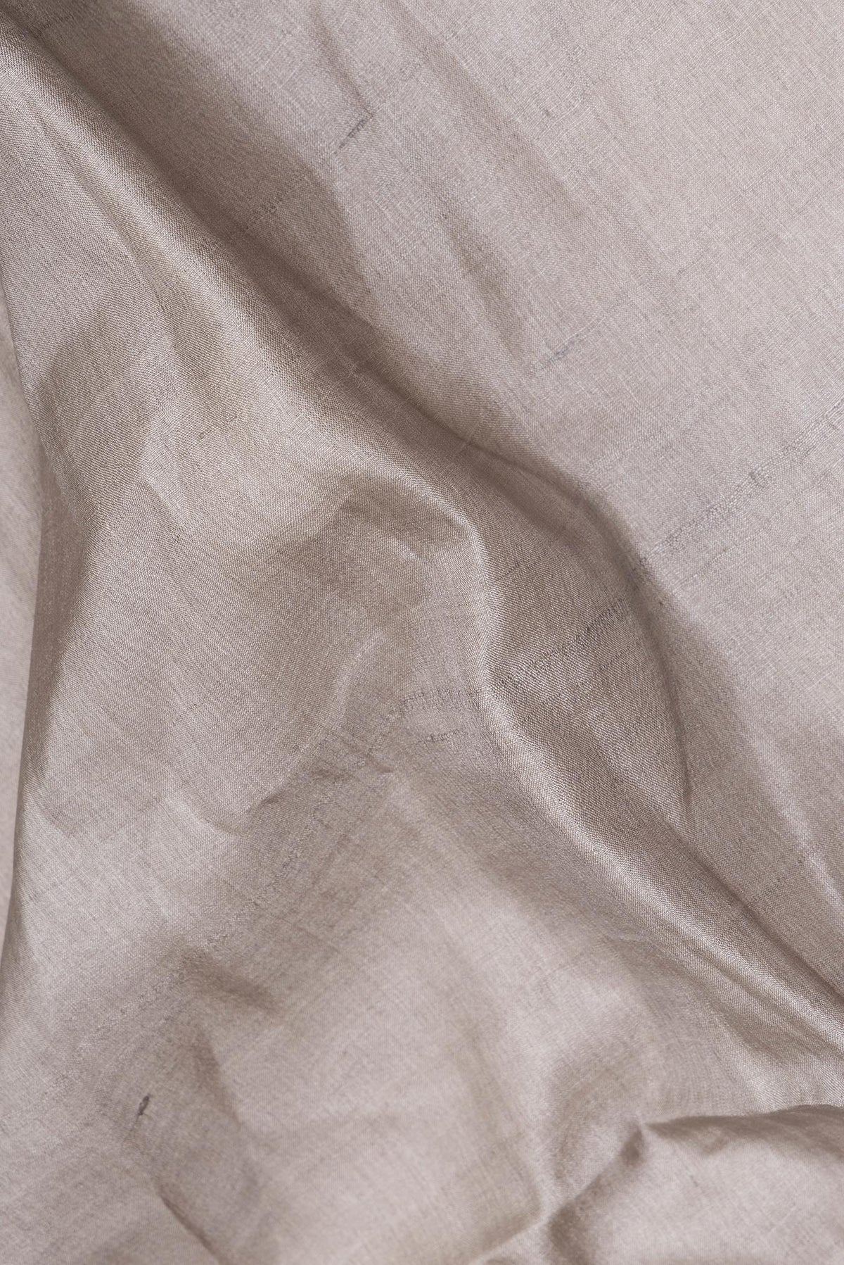 Close up of Pure Silk Grey Tussar Saree with Plain Body and Zari Border.  displaying folds