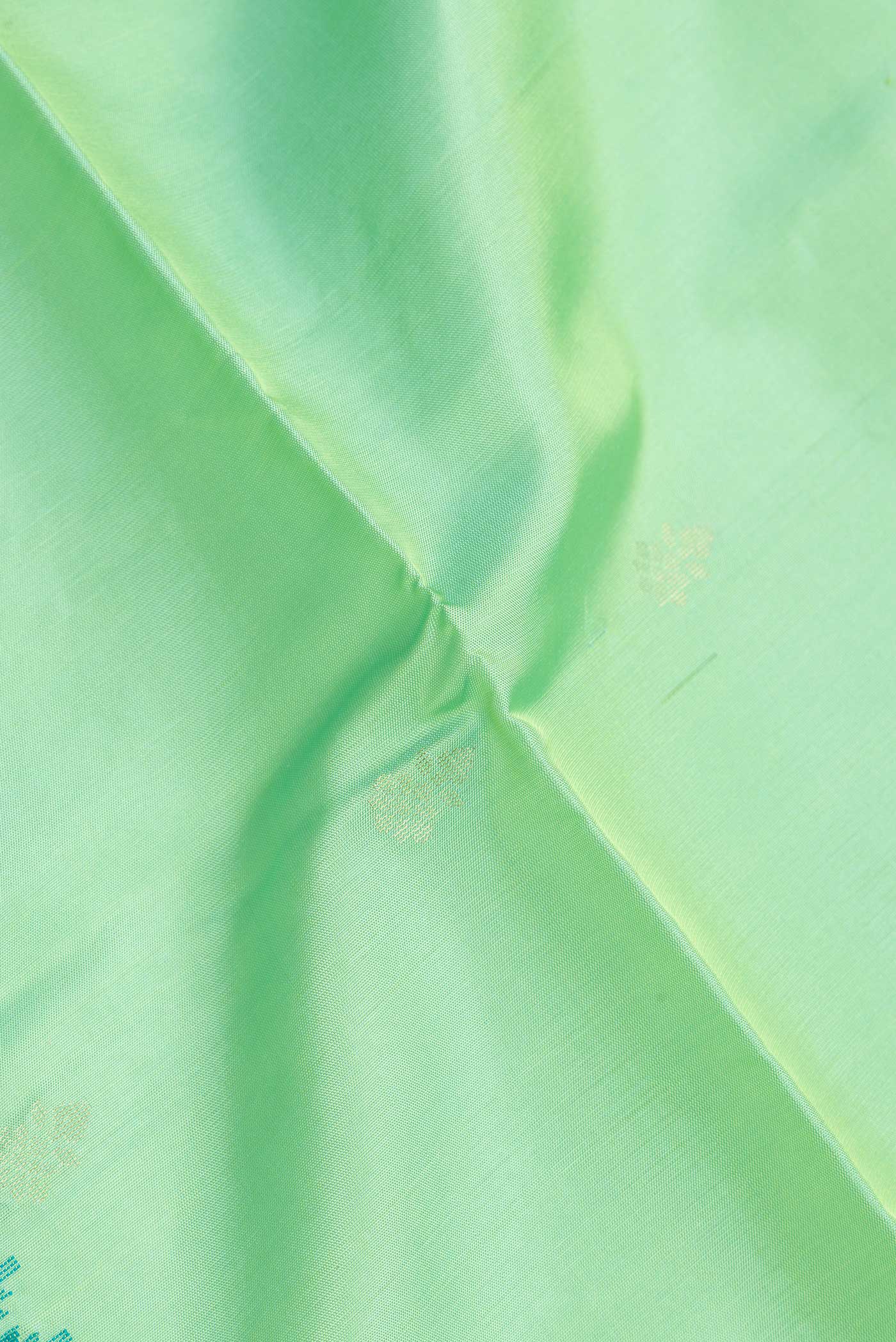 Close up of Pista Green Dual Tone Soft Silk Saree with Zari Butta on the body and Zari And Thread Border.  displaying folds