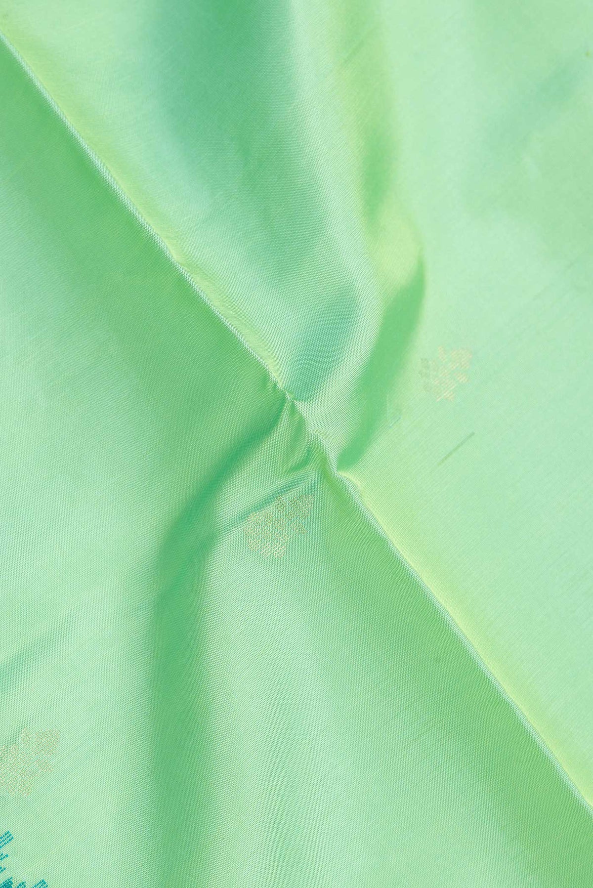 Close up of Pista Green Dual Tone Soft Silk Saree with Zari Butta on the body and Zari And Thread Border.  displaying folds