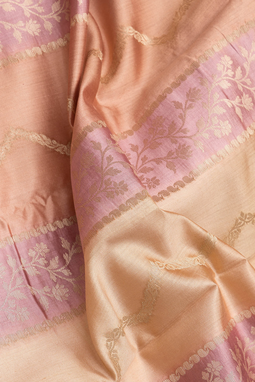 Close up of Rose Gold and Peach Color Banarasi Raw Silk Saree with Stripes on the body and Zari Border.  displaying folds