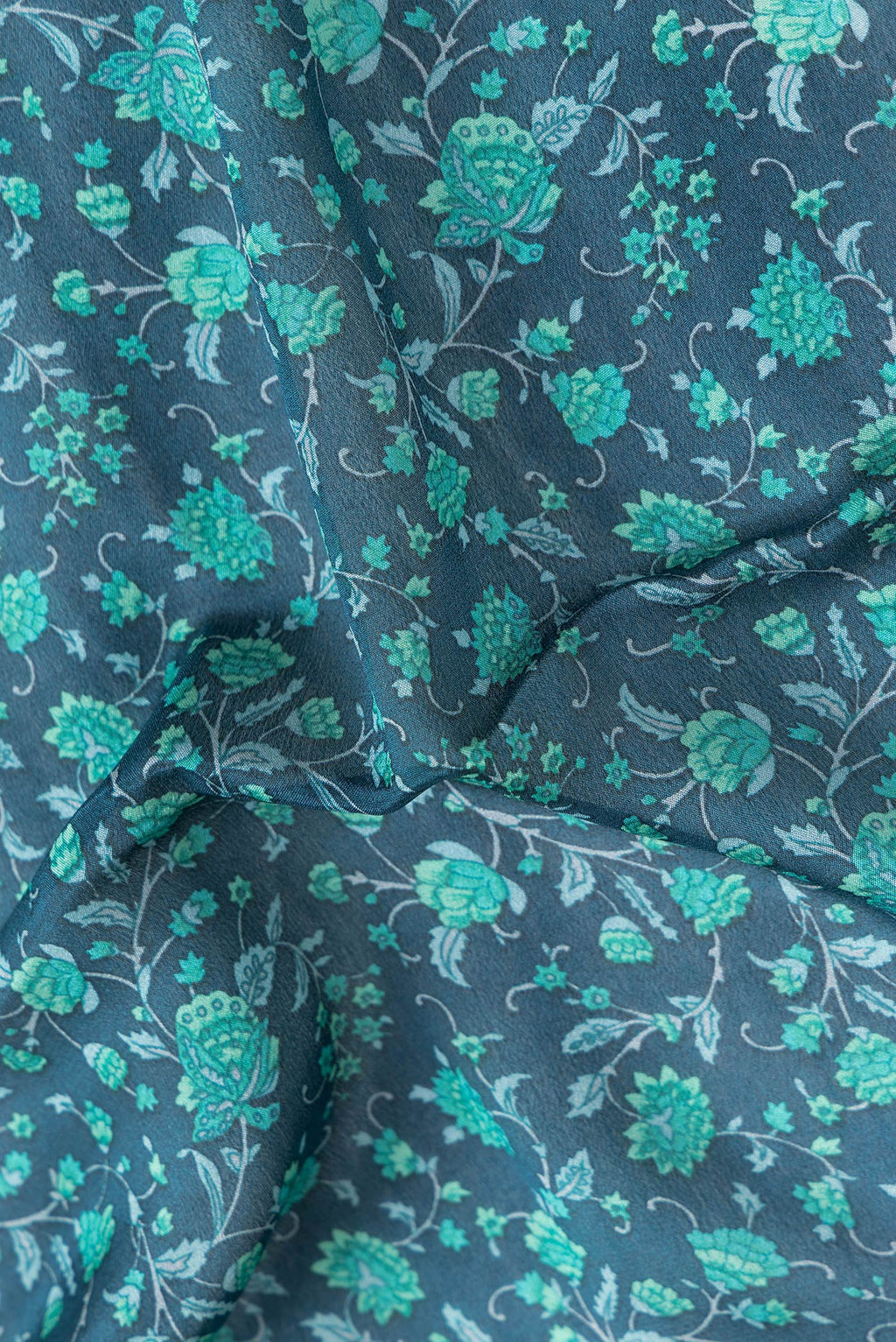 Close up of Peacock Blue Dual Tone Mysore Crepe Saree with Printed design on the body and Zari Border.  displaying folds