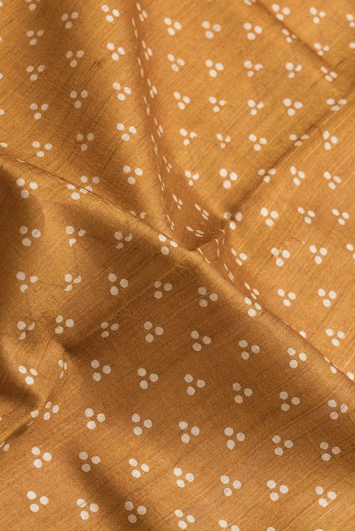 Close up of Mustard Dual Tone Tussar Silk Saree with Printed design on the body and Embroidery Border.  displaying folds