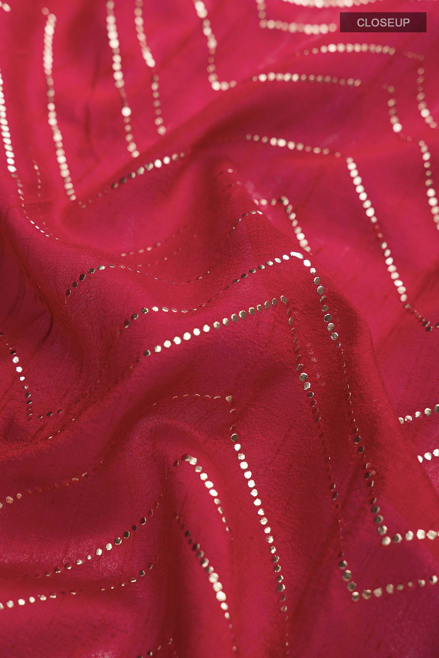 Close up of Red Raw Silk Saree with Embroidery on the body and Zari Border displaying folds