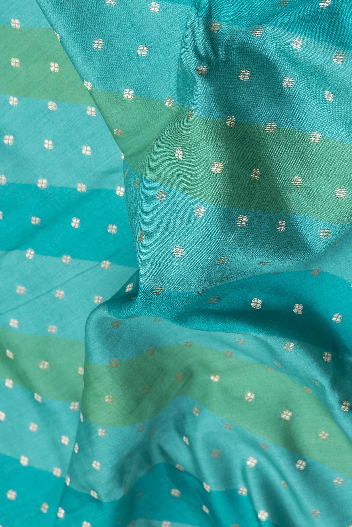 Close up of Sky Blue Dual Tone Tussar Silk Saree with Zari Butta on the body and Zari Border.  displaying folds
