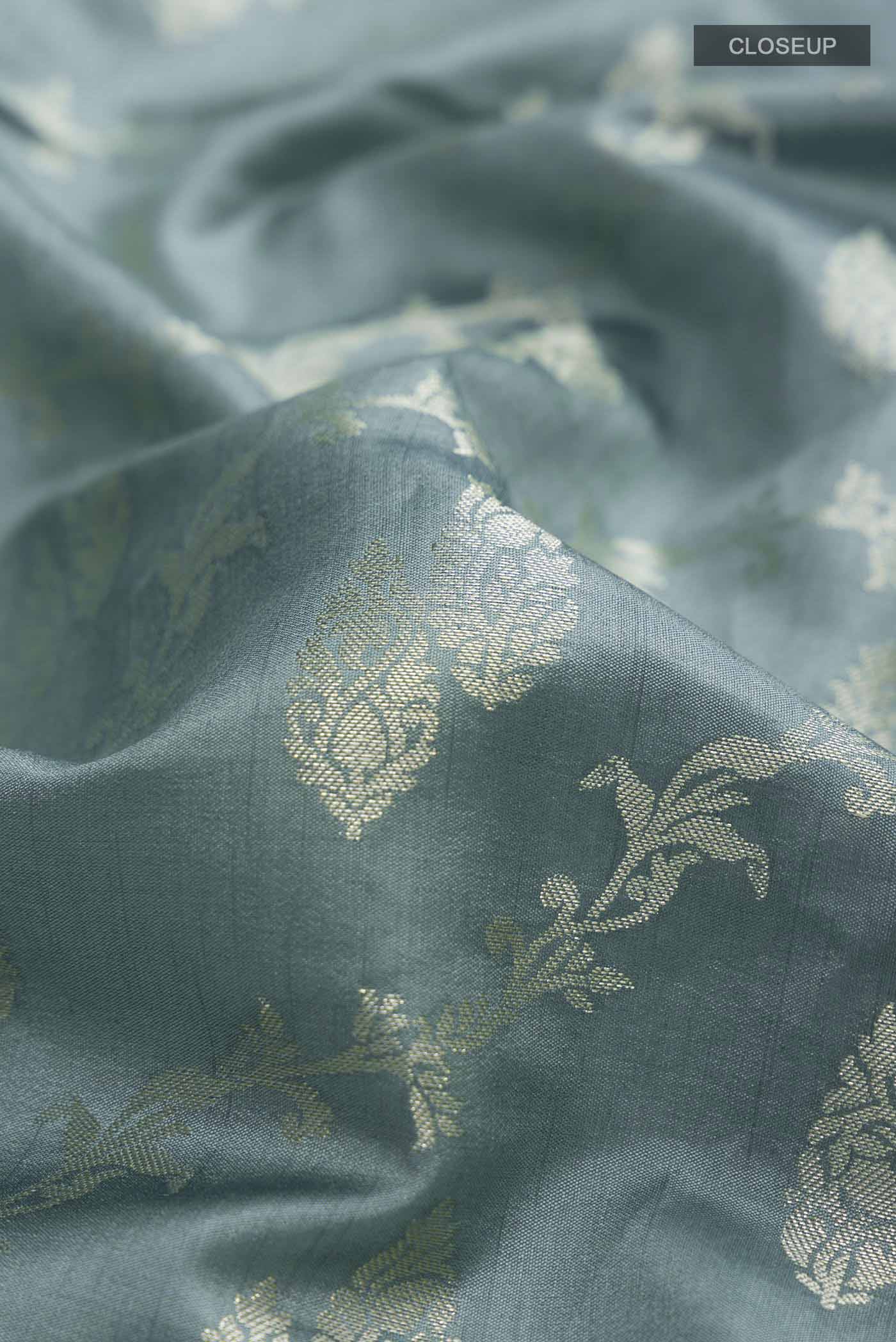 Close up of Green Banarasi Raw Silk Saree with Zari Butta on the body and Zari Border displaying folds