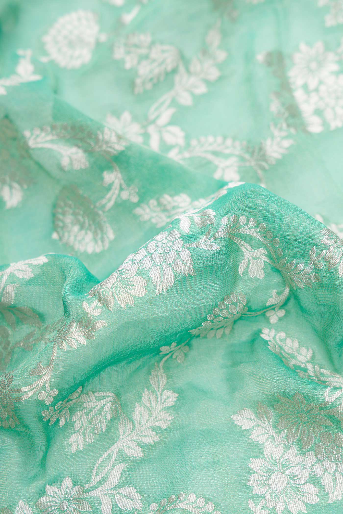 Close up of Green Dual Tone Banarasi Georgette Saree with Zari Brocade on the body and Zari Border.  displaying folds