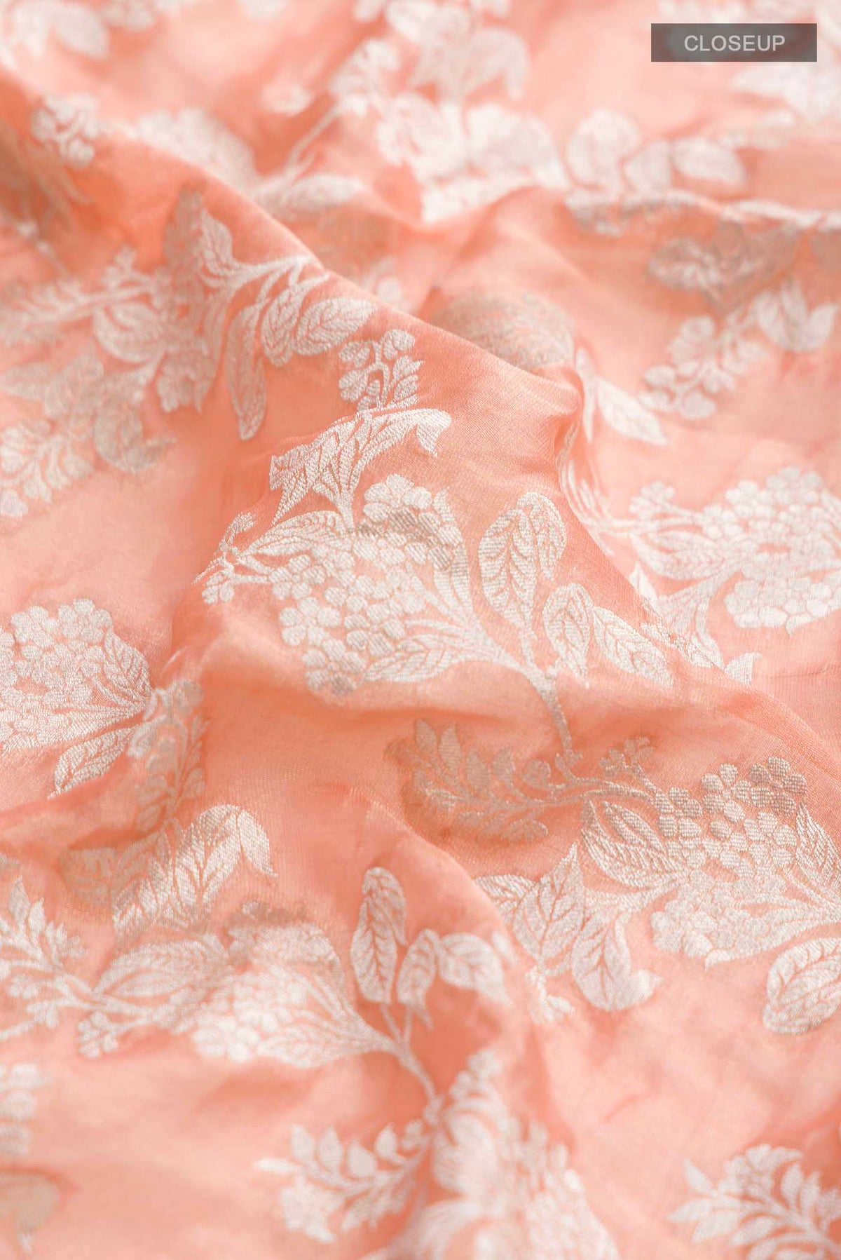 Close up of Peach Banarasi Georgette Saree with Zari Butta on the body and Zari Border displaying folds