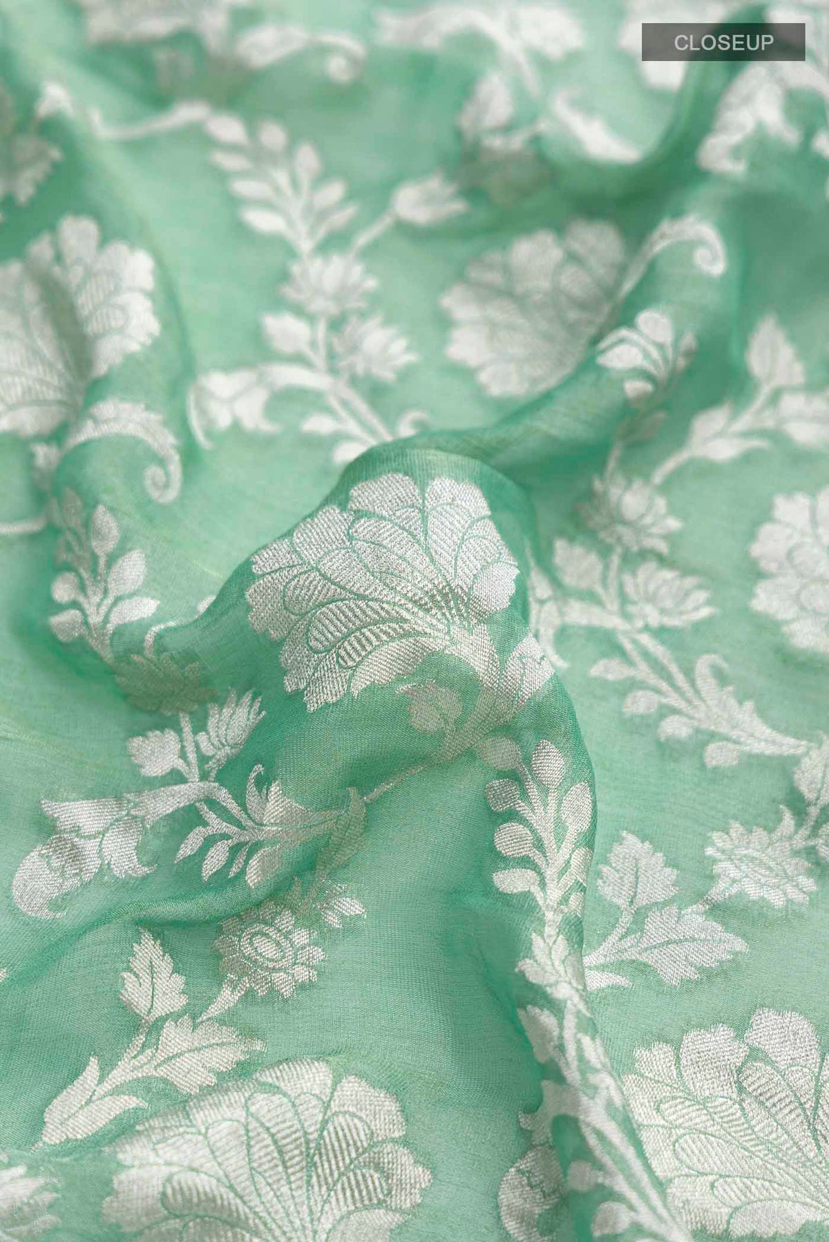 Close up of Green Banarasi Georgette Saree with Zari Butta on the body and Zari Border displaying folds
