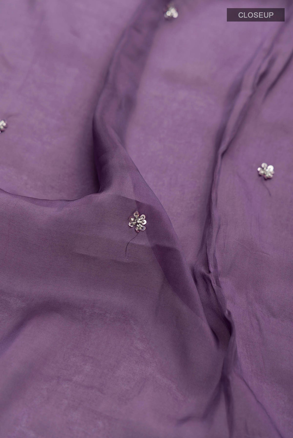 Close up of Lilac Satin Silk Saree with Plain Body and Embroidery Border displaying folds