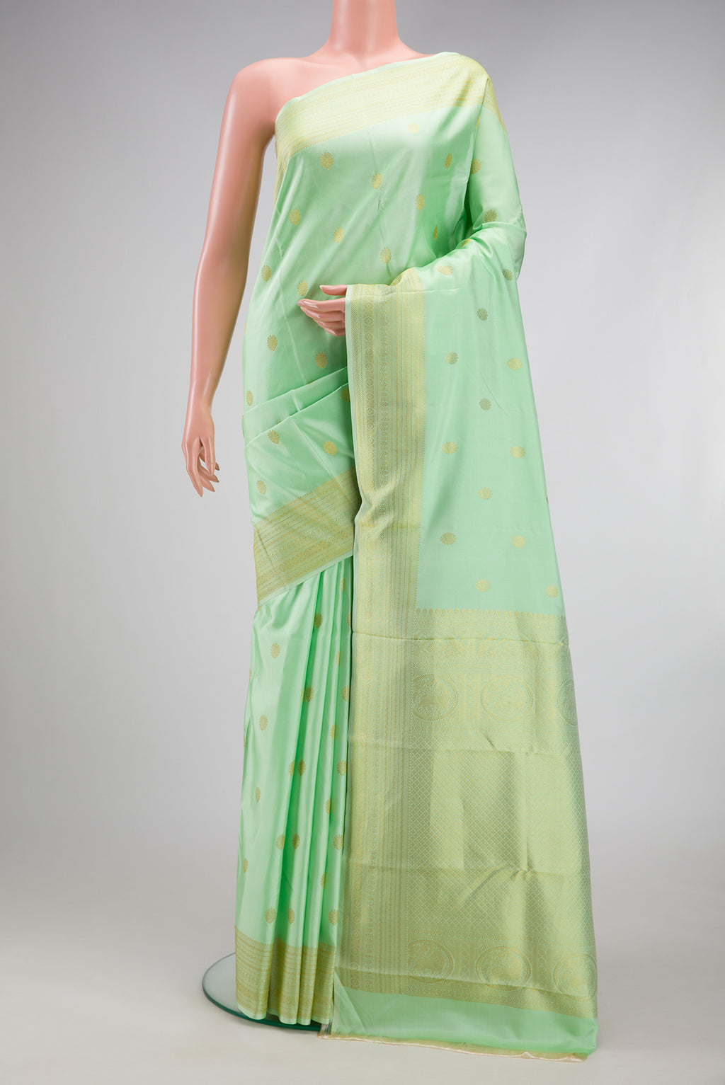 Pista Green Kanchipuram Silk Saree with Zari Butta on the body and Zari Border.  displayed on a mannequin