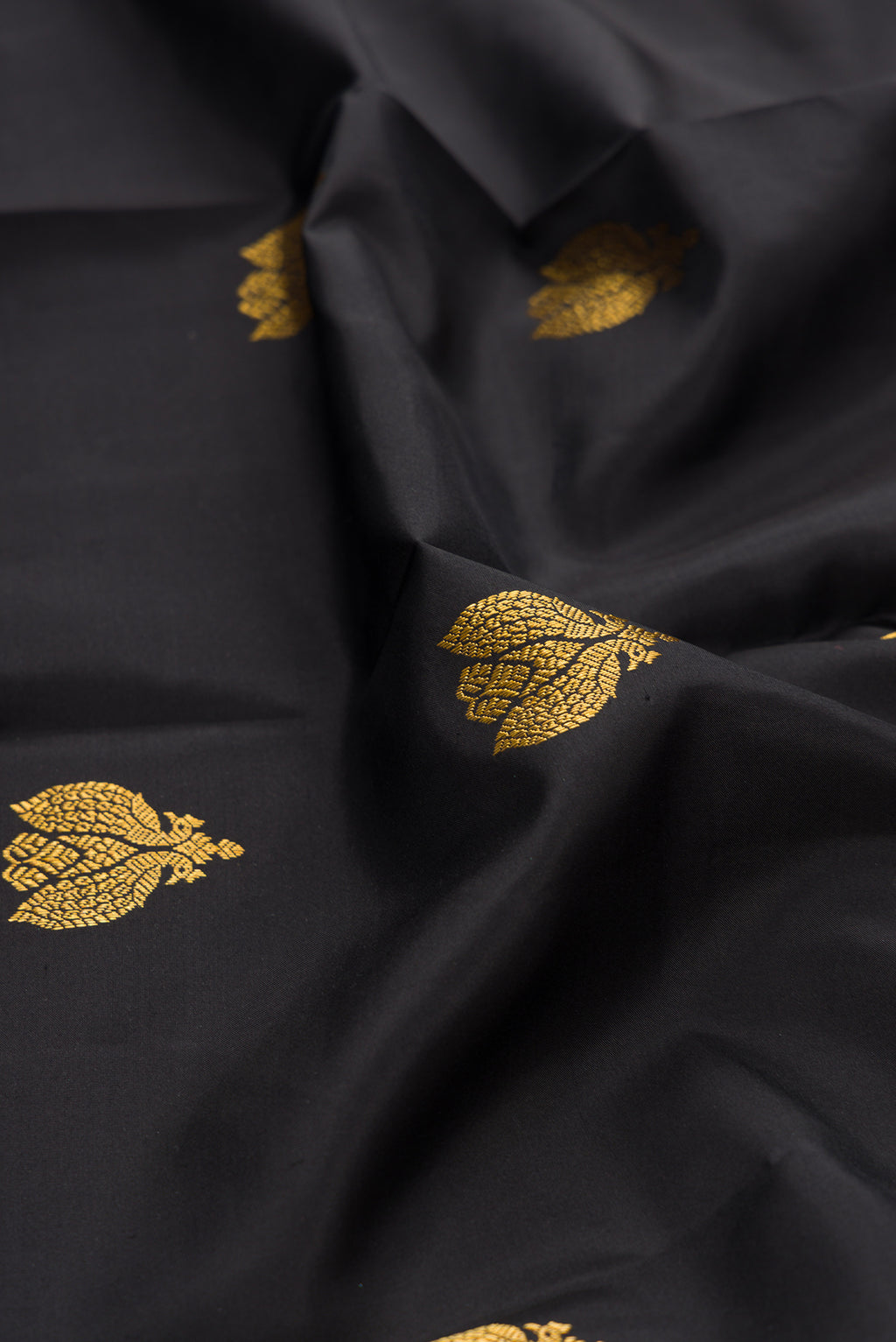 Close up of Black Kanjivaram Silk Saree with Zari Butta on the body and Zari And Thread Border.  displaying folds
