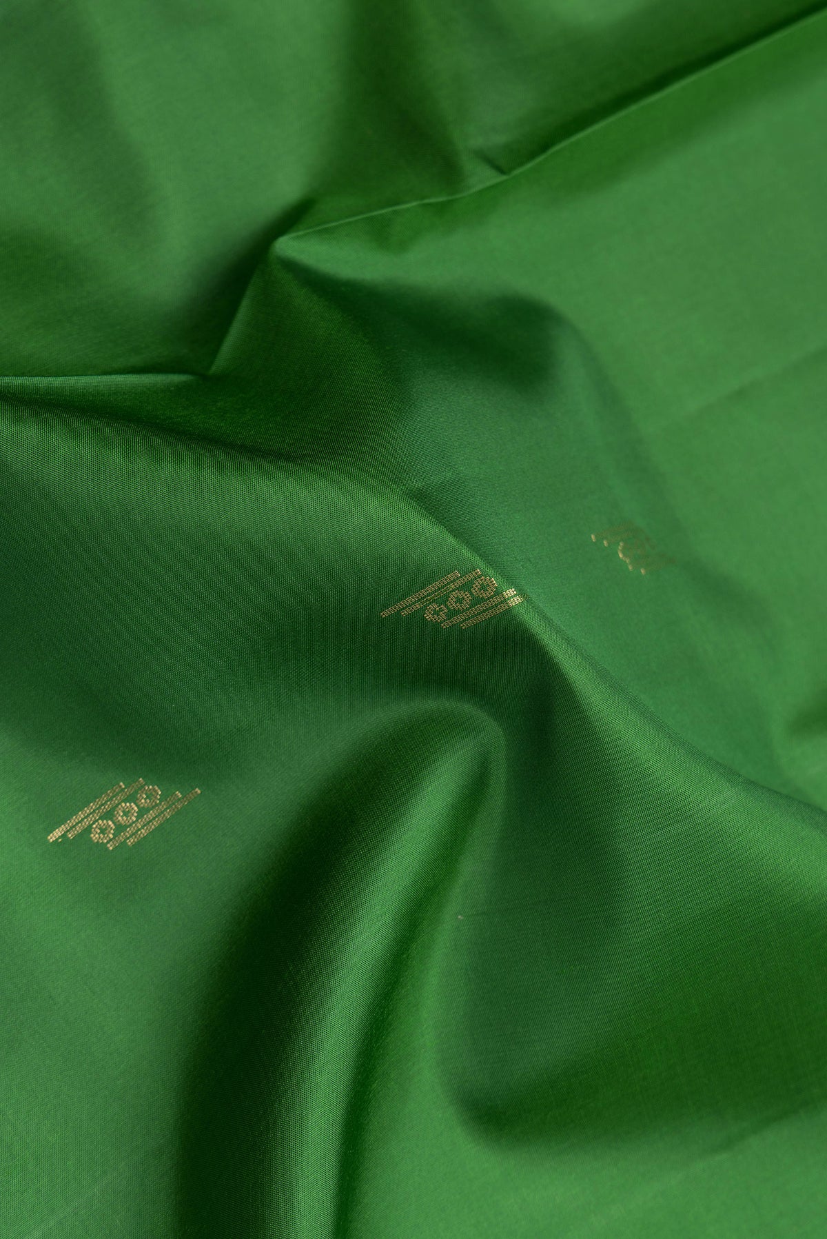 Close up of Green Dual Tone Soft Silk Saree with Zari Butta on the body and Zari Border.  displaying folds