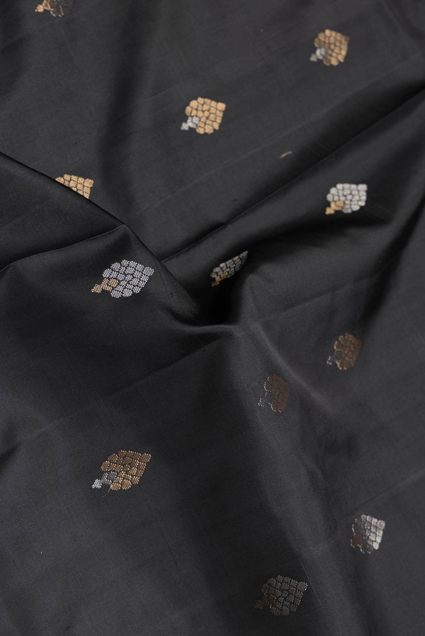 Close up of Black Dual Tone Soft Silk Saree with Zari Butta on the body and Zari Border.  displaying folds