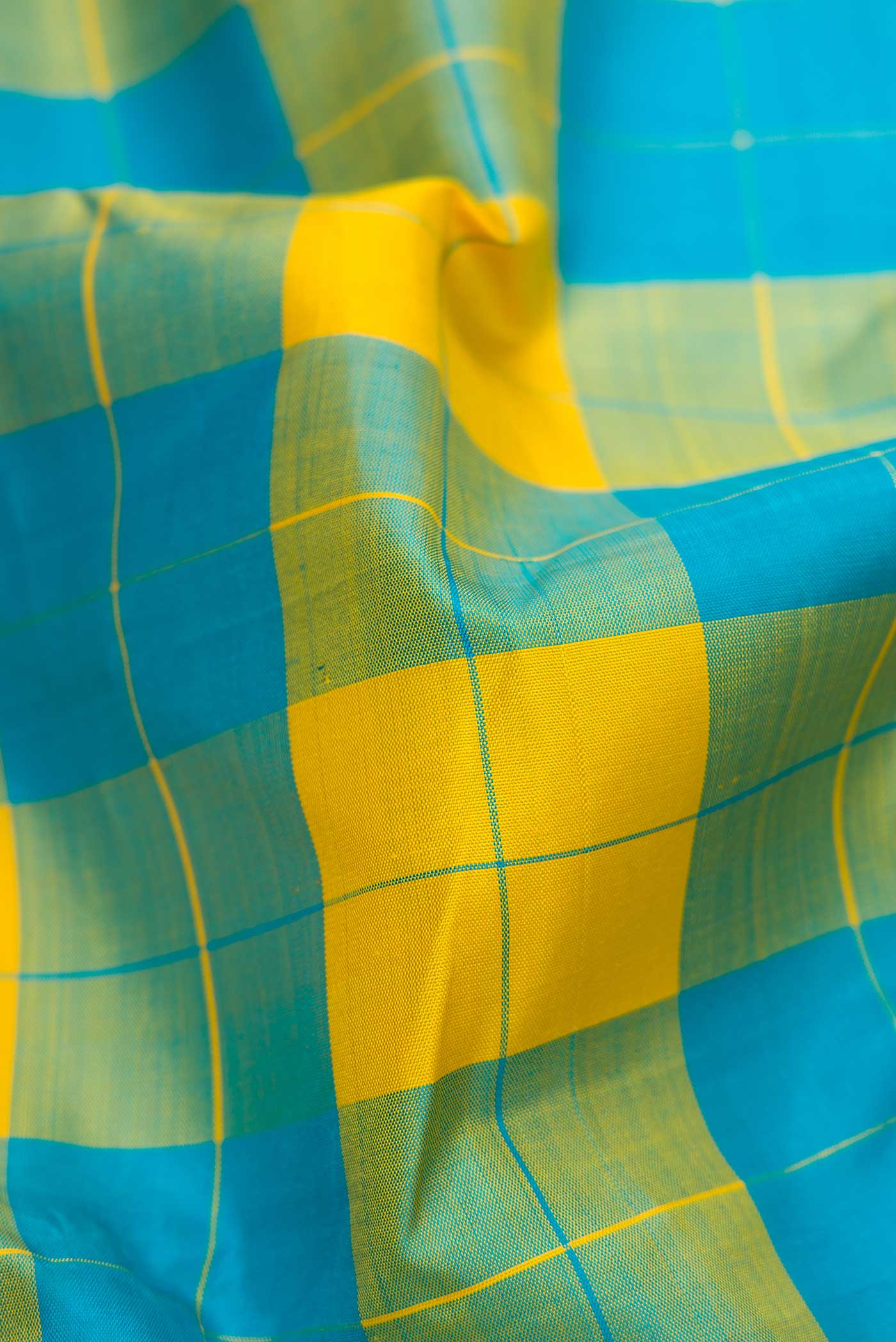 Close up of Green and Yellow Color Kanchipuram Silk Saree with Checked design on the body and Thread Border displaying folds
