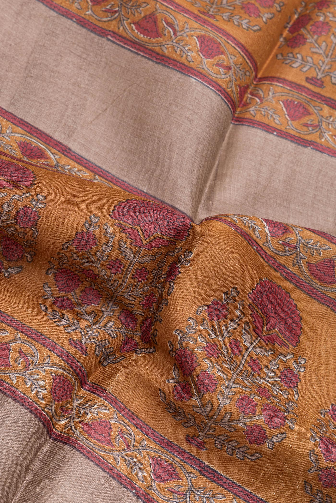Close up of Brown Tussar Silk Saree with Printed design on the body and Zari Border.  displaying folds