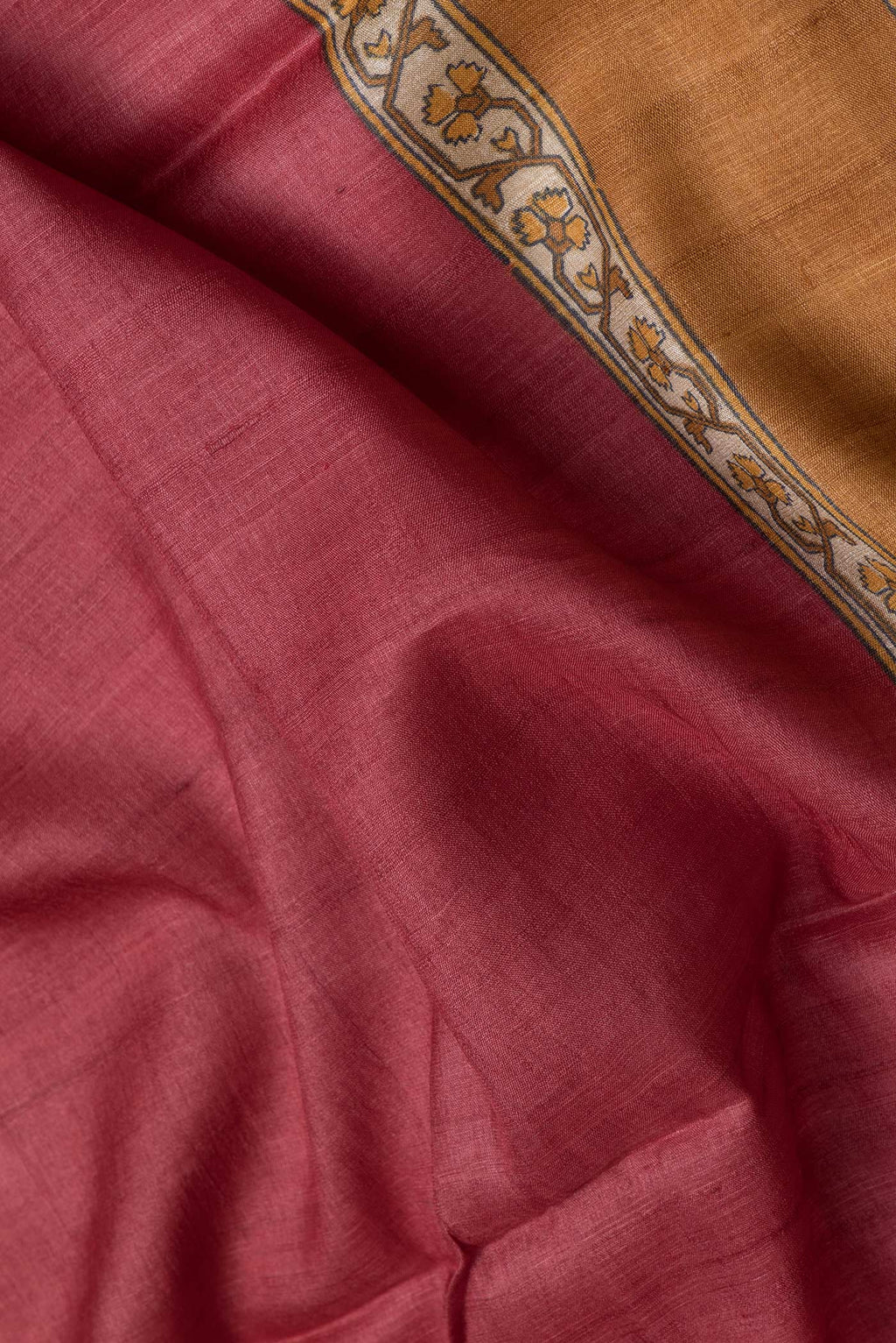 Close up of Maroon Dual Tone Tussar Silk Saree with Printed design on the body and Zari Border.  displaying folds