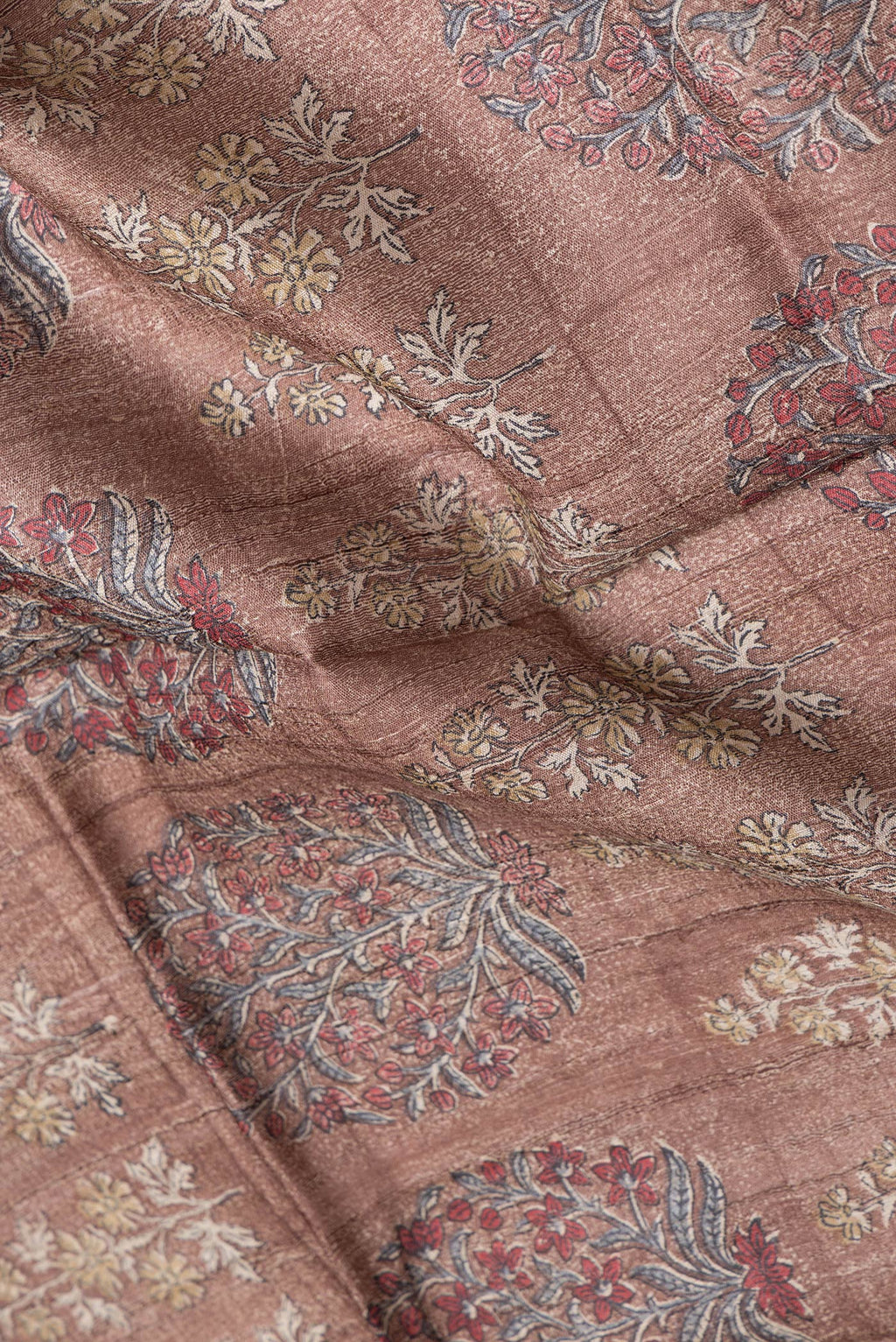 Close up of Brown Dual Tone Tussar Silk Saree with Printed design on the body and Zari Border.  displaying folds