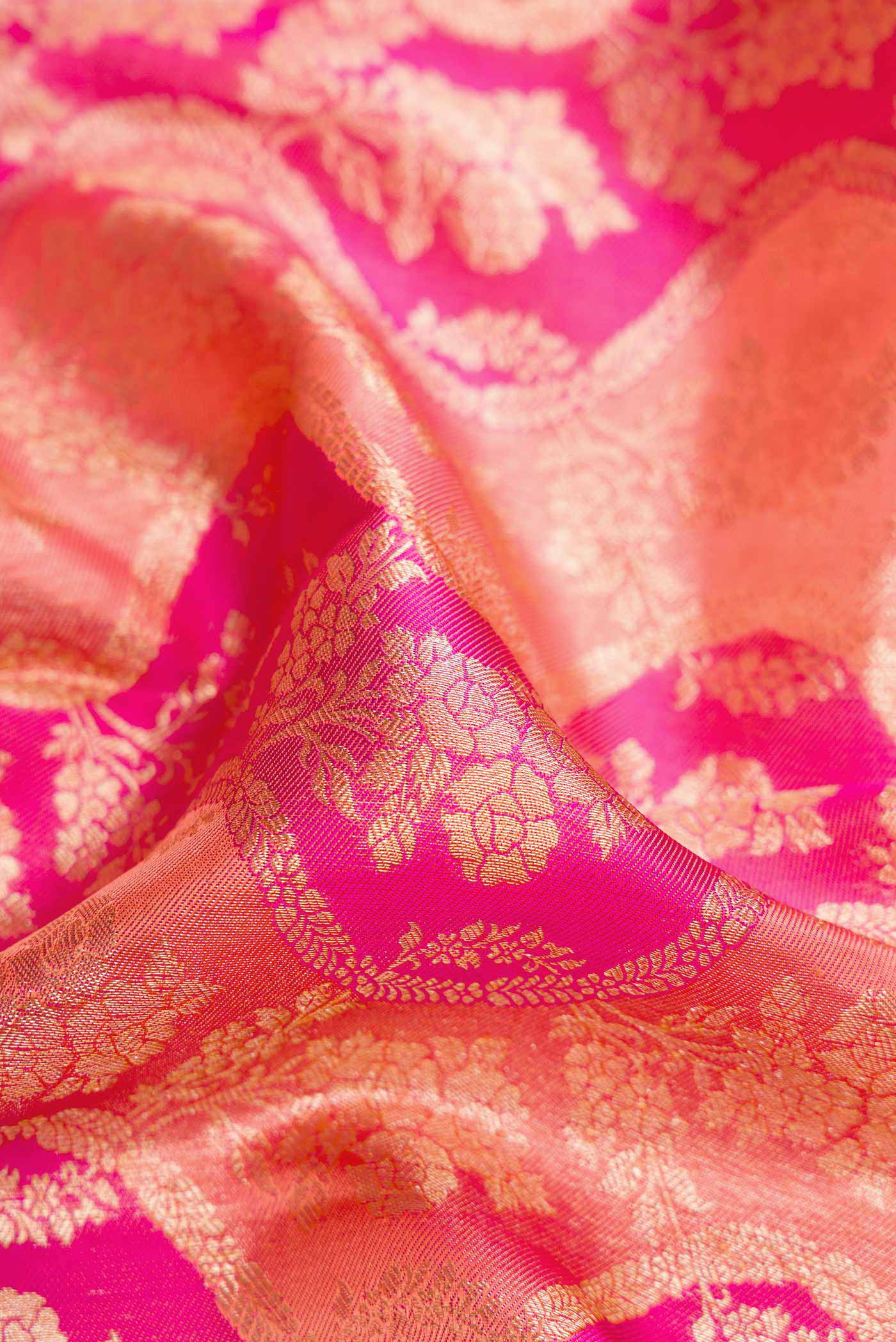Close up of Golden Peach and Pink Color Kanjivaram Silk Saree with Zari Brocade on the body and Zari Border.  displaying folds