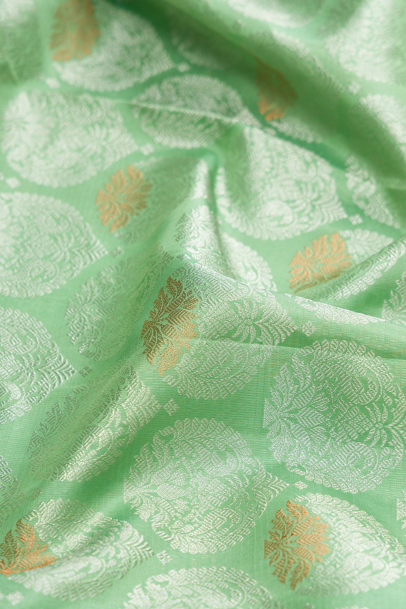 Close up of Light Green Dual Tone Kanchipuram Silk Saree with Zari Brocade on the body and Zari Border.  displaying folds