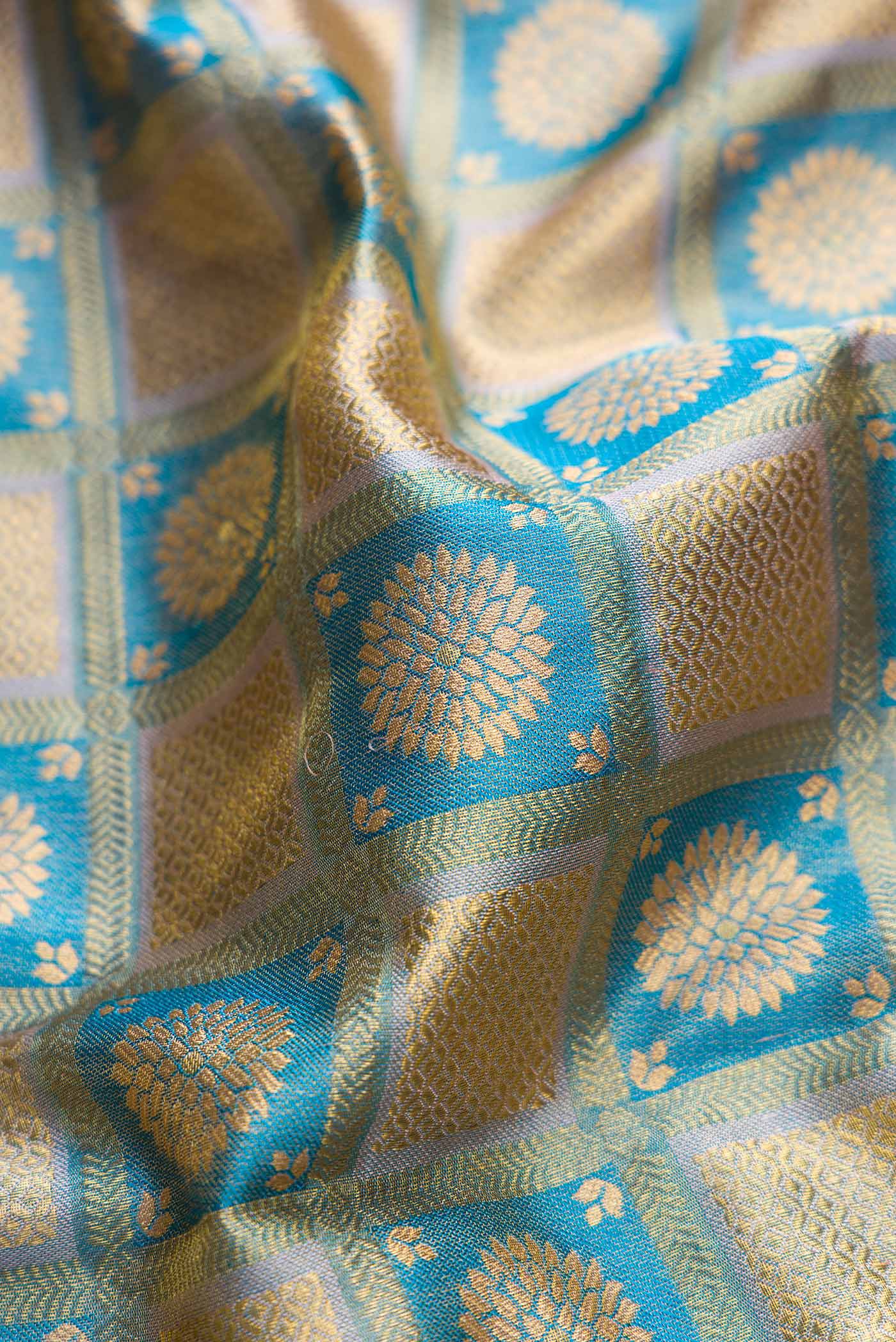 Close up of Peacock Blue Dual Tone Kanchipuram Tissue Silk Saree with Zari Brocade on the body and Fancy Border displaying folds