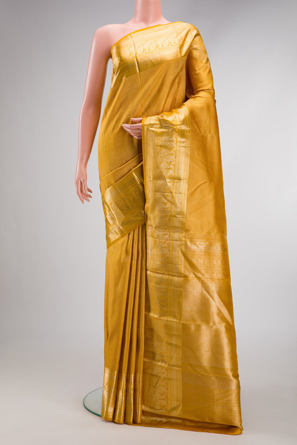 Mustard Kanchipuram Silk Saree with Zari Brocade on the body and Zari Border.  displayed on a mannequin