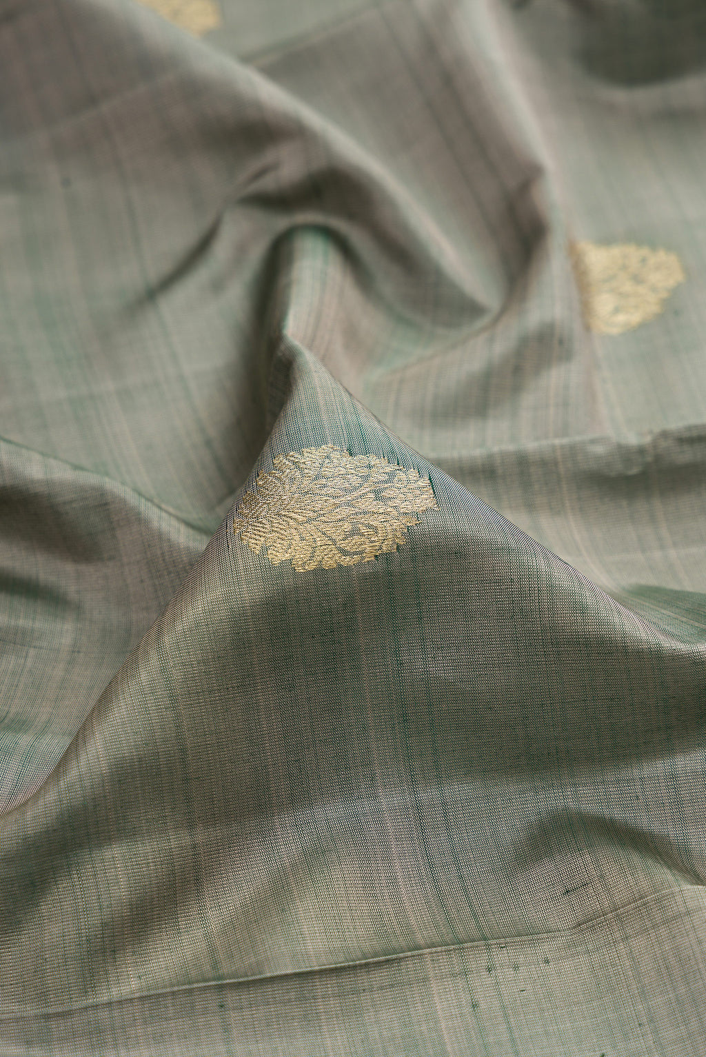 Close up of Grey Kanchipuram Silk Saree with Zari Butta on the body and Zari Border.  displaying folds