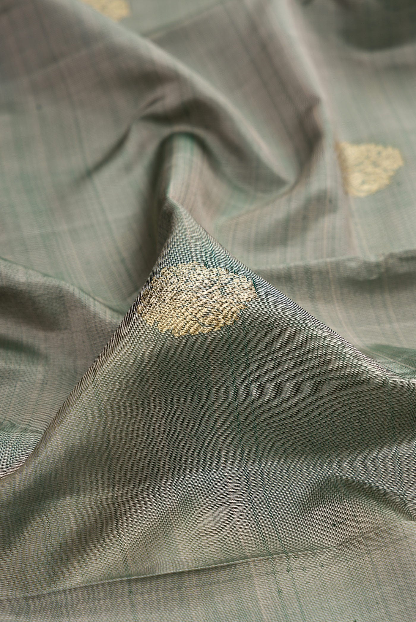 Close up of Grey Kanchipuram Silk Saree with Zari Butta on the body and Zari Border.  displaying folds