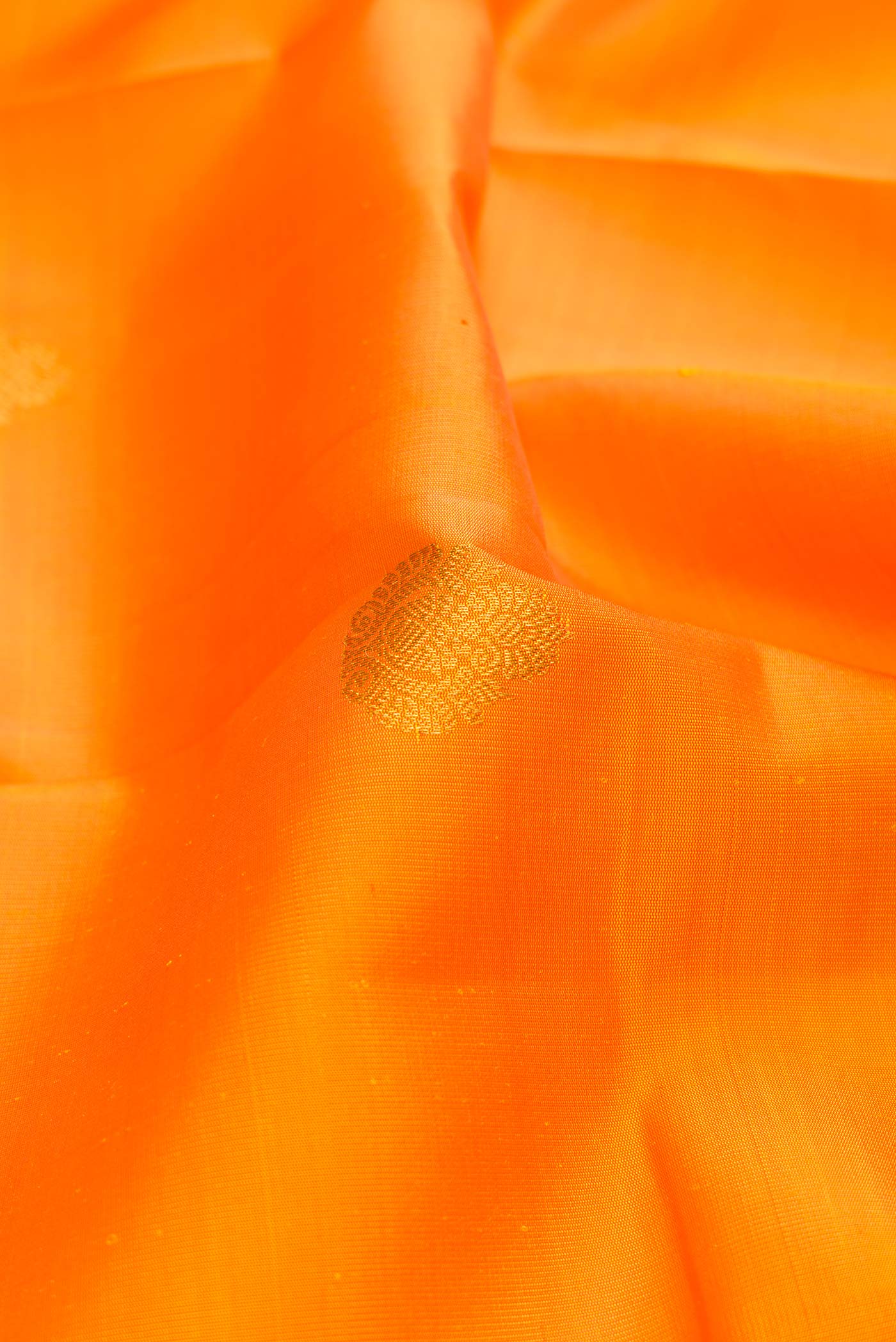 Close up of Orange Dual Tone Kanchipuram Saree with Zari Butta on the body and Zari Border displaying folds