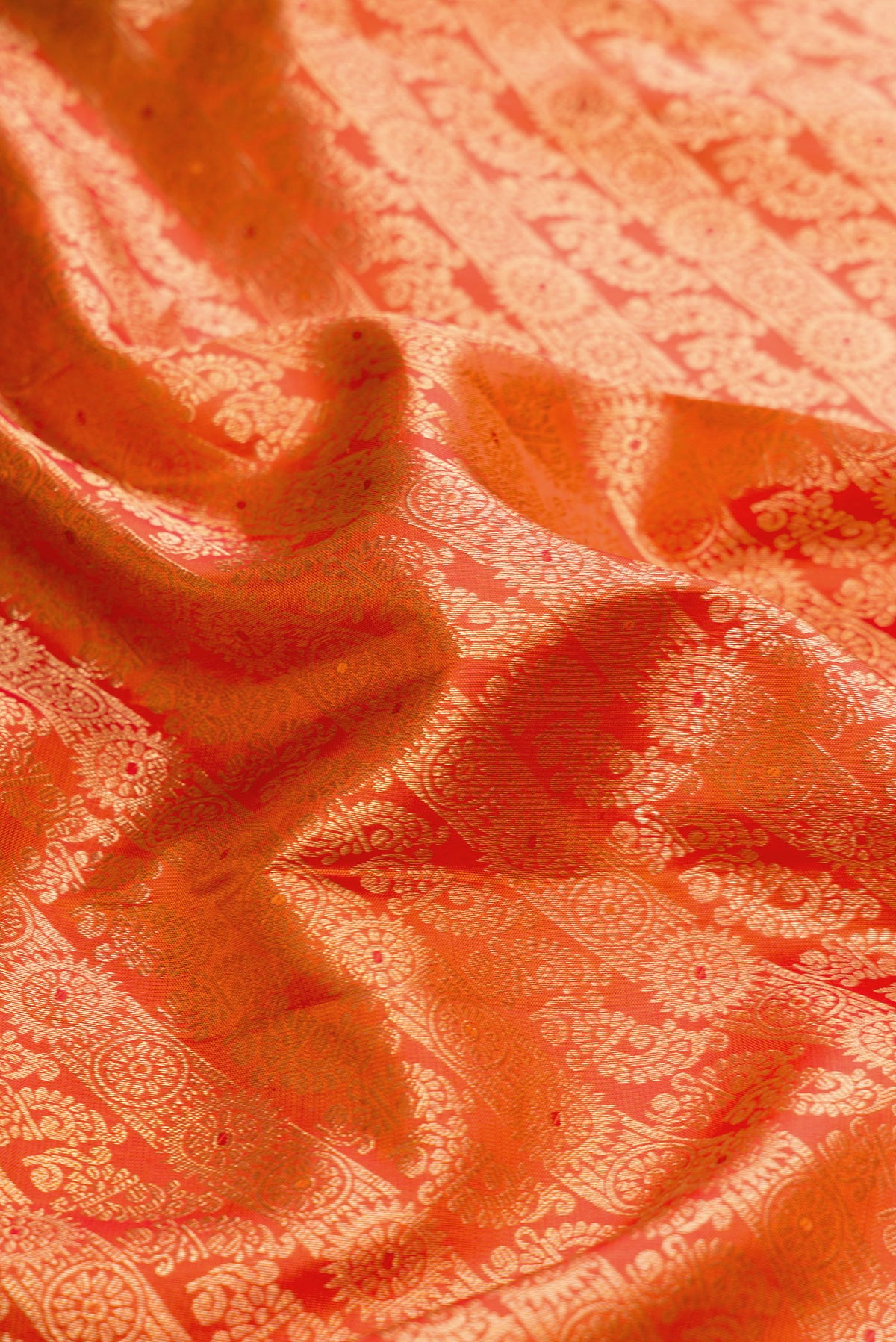 Close up of Orange Dual Tone Kanjivaram Silk Saree with Zari Brocade on the body and Zari Border.  displaying folds