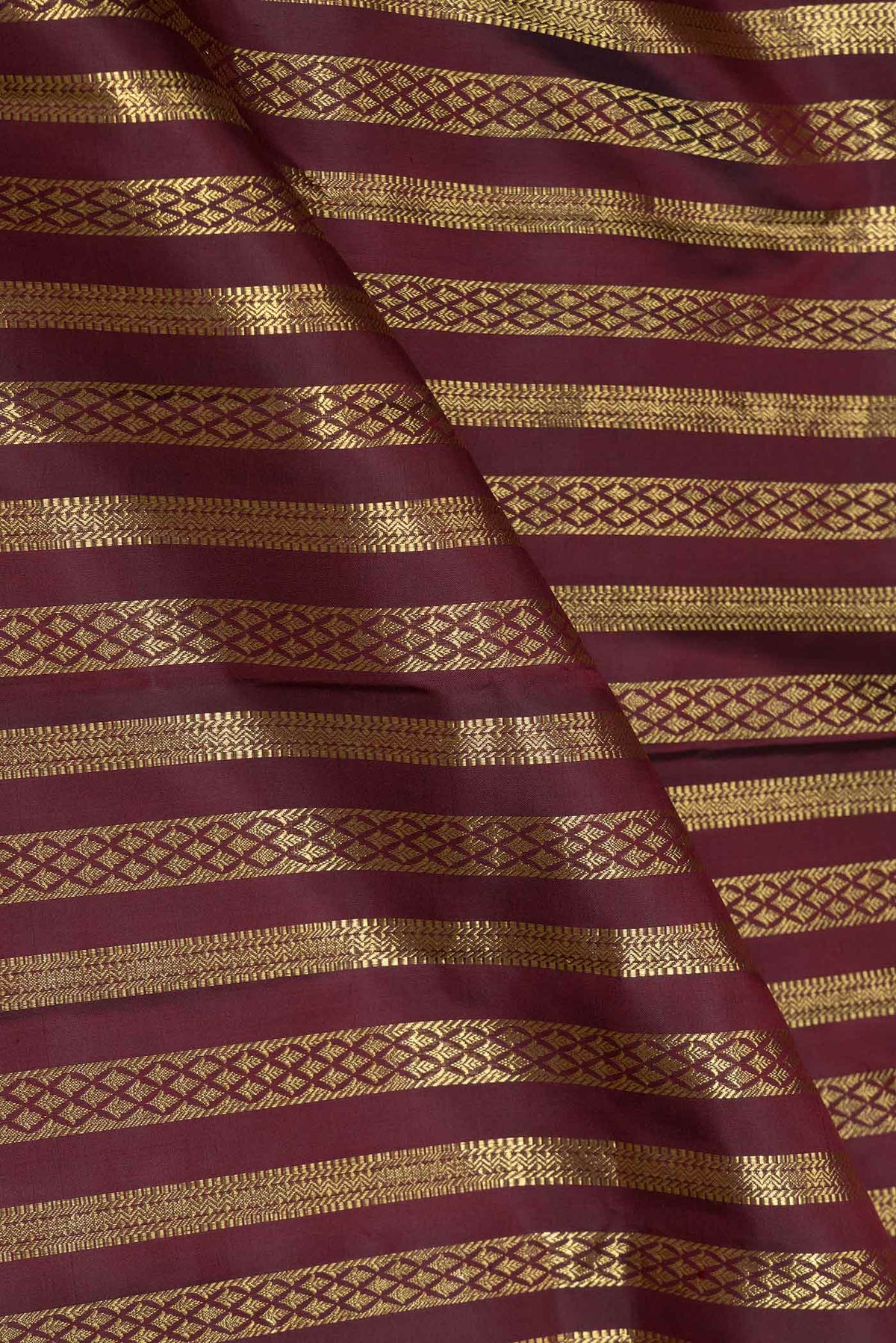 Close up of Maroon Dual Tone Kanchipuram Saree with Stripes on the body and Zari Border displaying folds