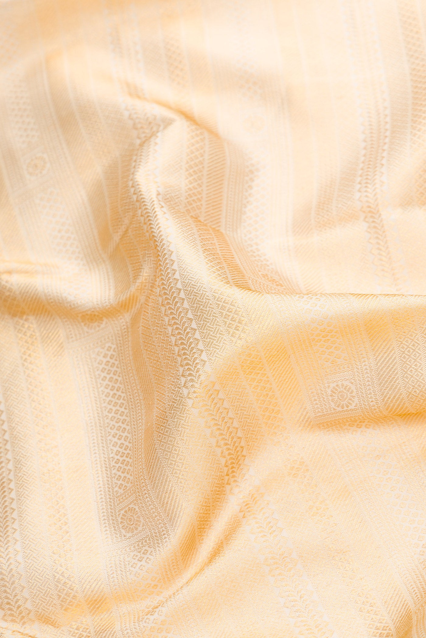 Close up of Off White Dual Tone Kanjivaram Silk Saree with Zari Brocade on the body and Zari Border.  displaying folds