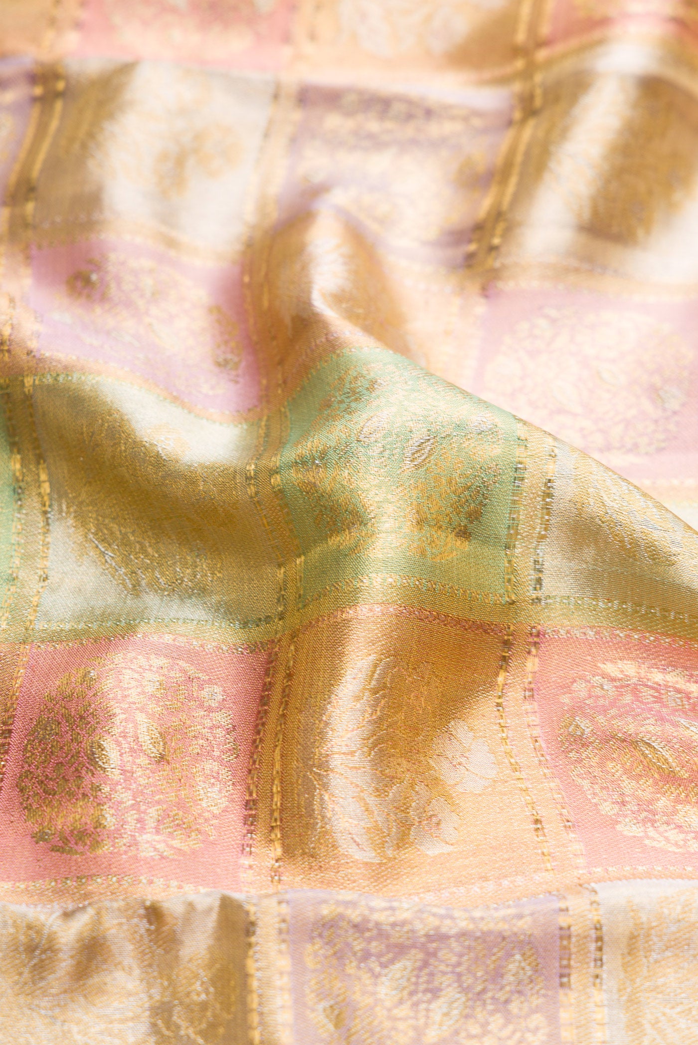 Close up of Gold, Pink and Green Color Kanjivaram Tissue Silk Saree with Zari Brocade on the body and Zari Border.  displaying folds