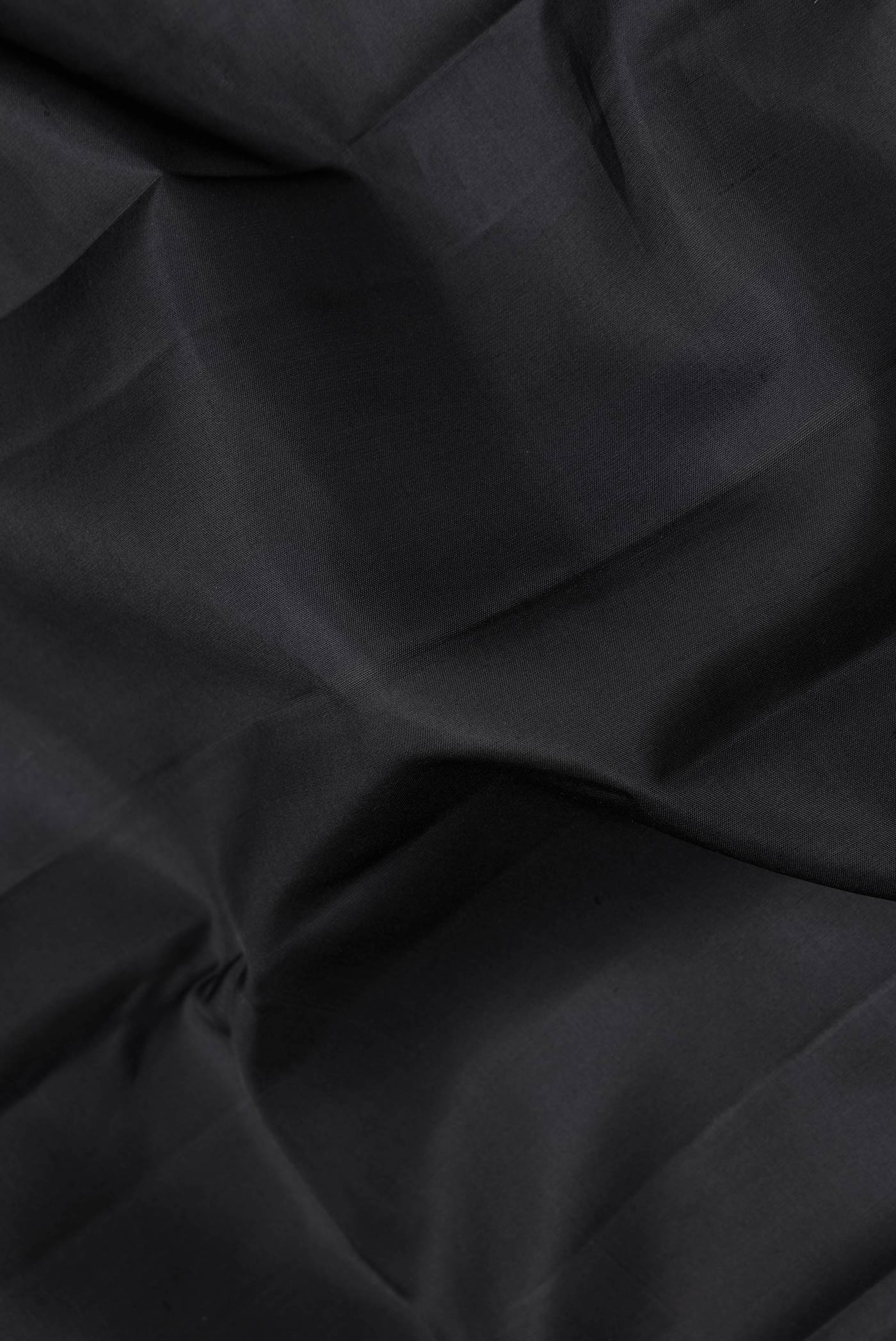 Close up of Black Dual Tone Kanchipuram Saree with Plain Body and Fancy Border.  displaying folds