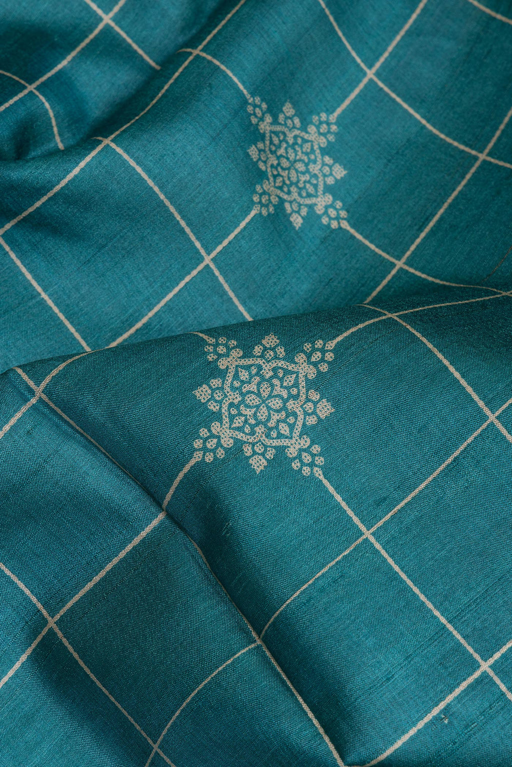 Close up of Peacock Blue Tussar Silk Saree with Checked design on the body and Zari Border.  displaying folds