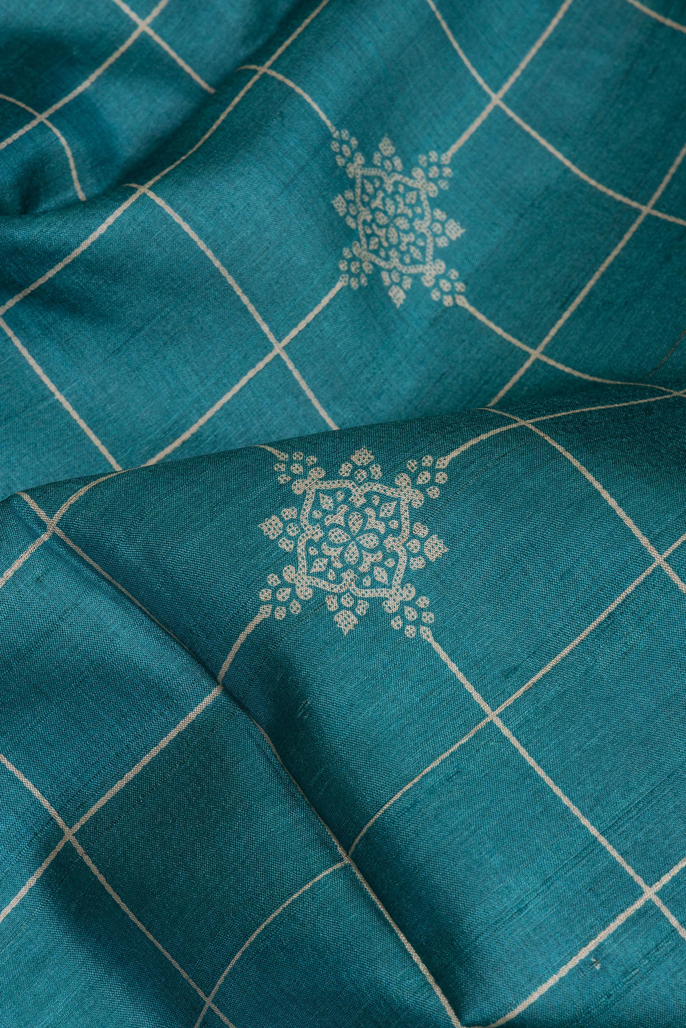 Close up of Peacock Blue Tussar Silk Saree with Checked design on the body and Zari Border.  displaying folds