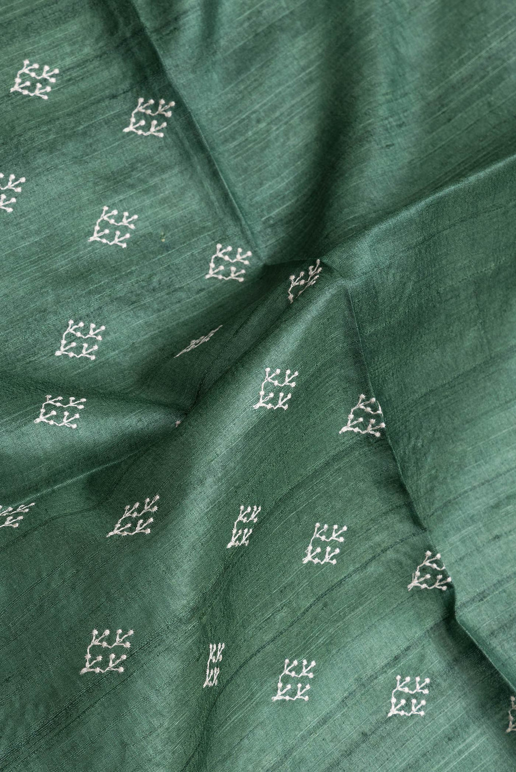 Close up of Green Dual Tone Tussar Silk Saree with Embroidery on the body and Zari Border.  displaying folds