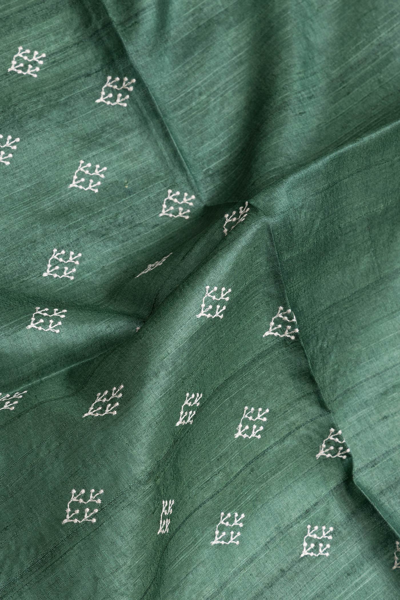 Close up of Green Dual Tone Tussar Silk Saree with Embroidery on the body and Zari Border.  displaying folds