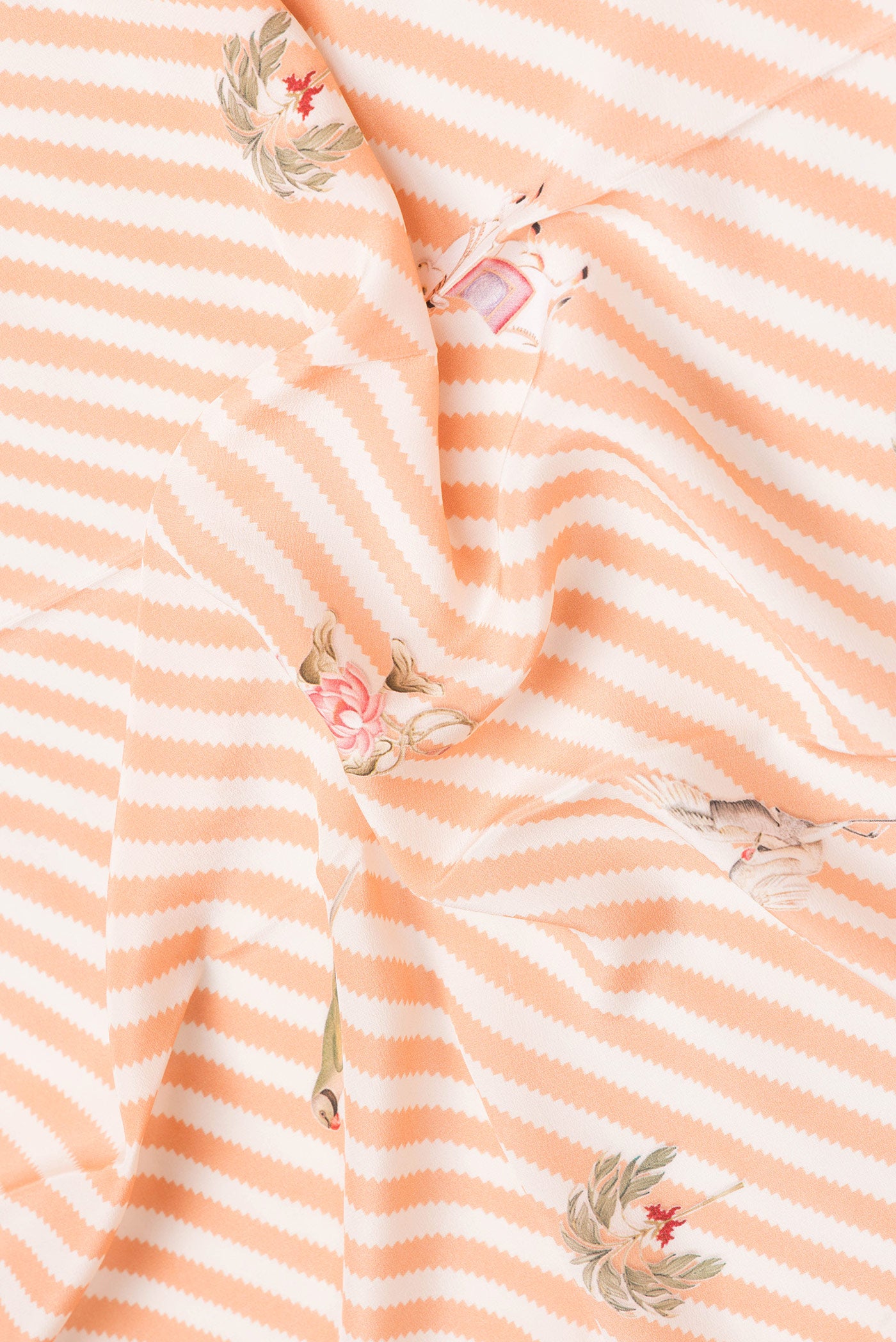 Close up of Orange Dual Tone Mysore Crepe Saree with Printed design on the body and Fancy Border.  displaying folds
