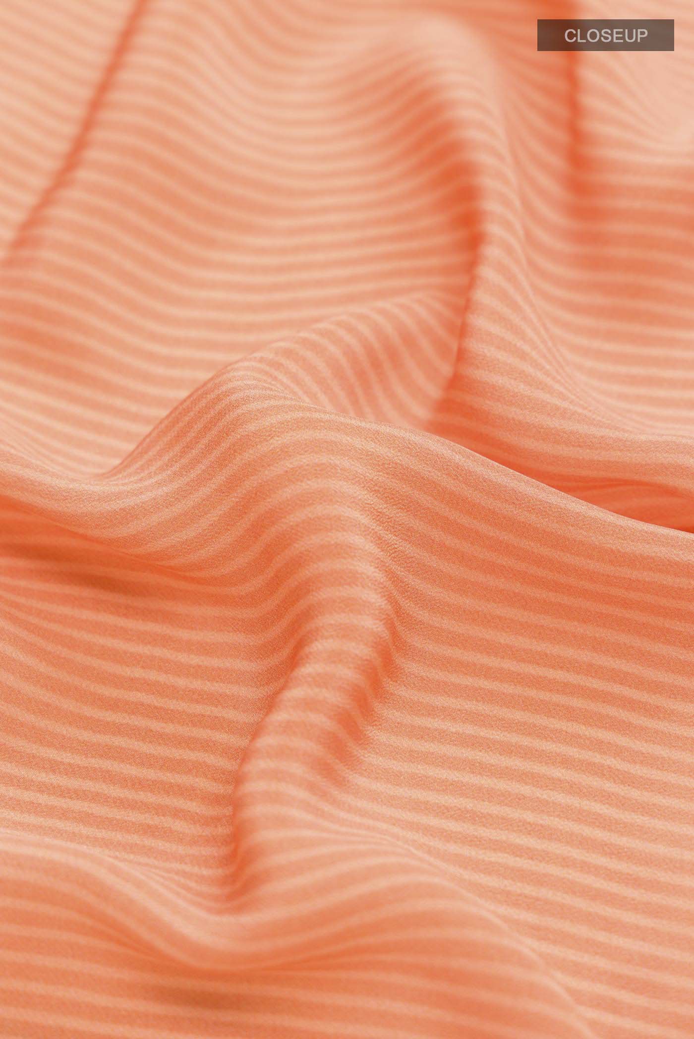 Close up of Orange Mysore Crepe Saree with Stripes on the body and Printed Border displaying folds