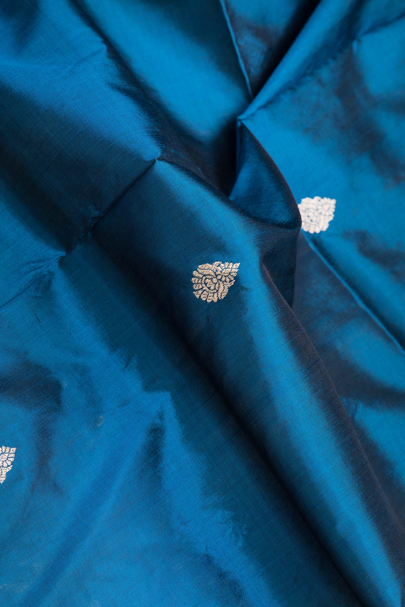 Close up of Peacock Blue Dual Tone Banarasi Silk Saree with Zari Butta on the body and Zari Border.  displaying folds