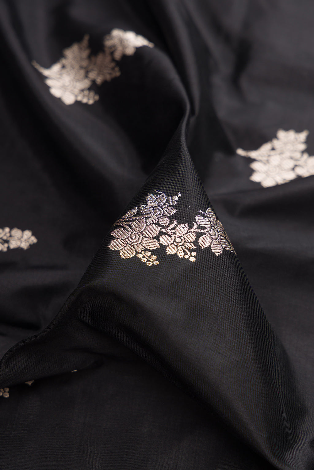 Close up of Black Banarasi Katan Silk Saree with Zari Butta on the body and Fancy Border.  displaying folds