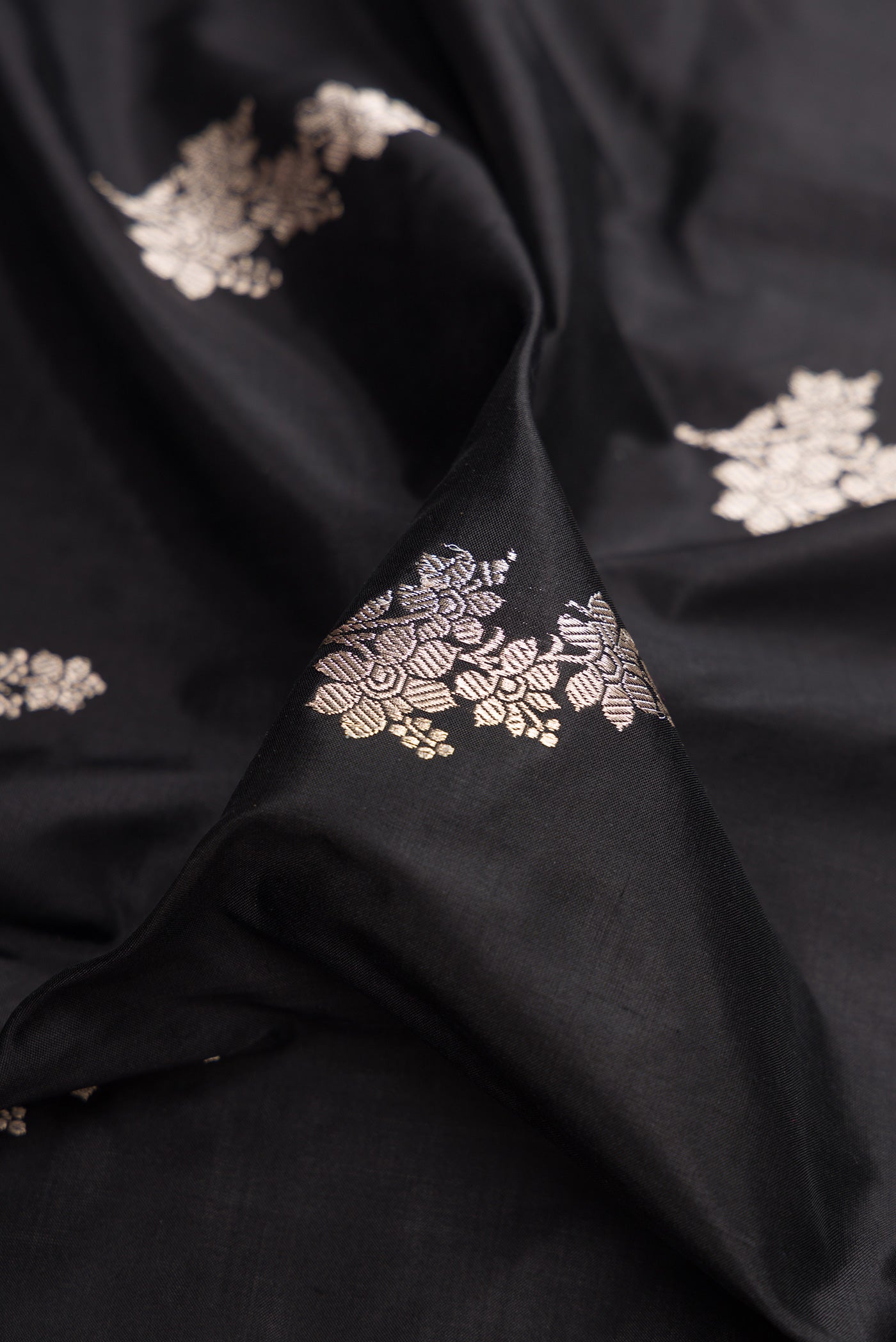 Close up of Black Banarasi Katan Silk Saree with Zari Butta on the body and Fancy Border.  displaying folds