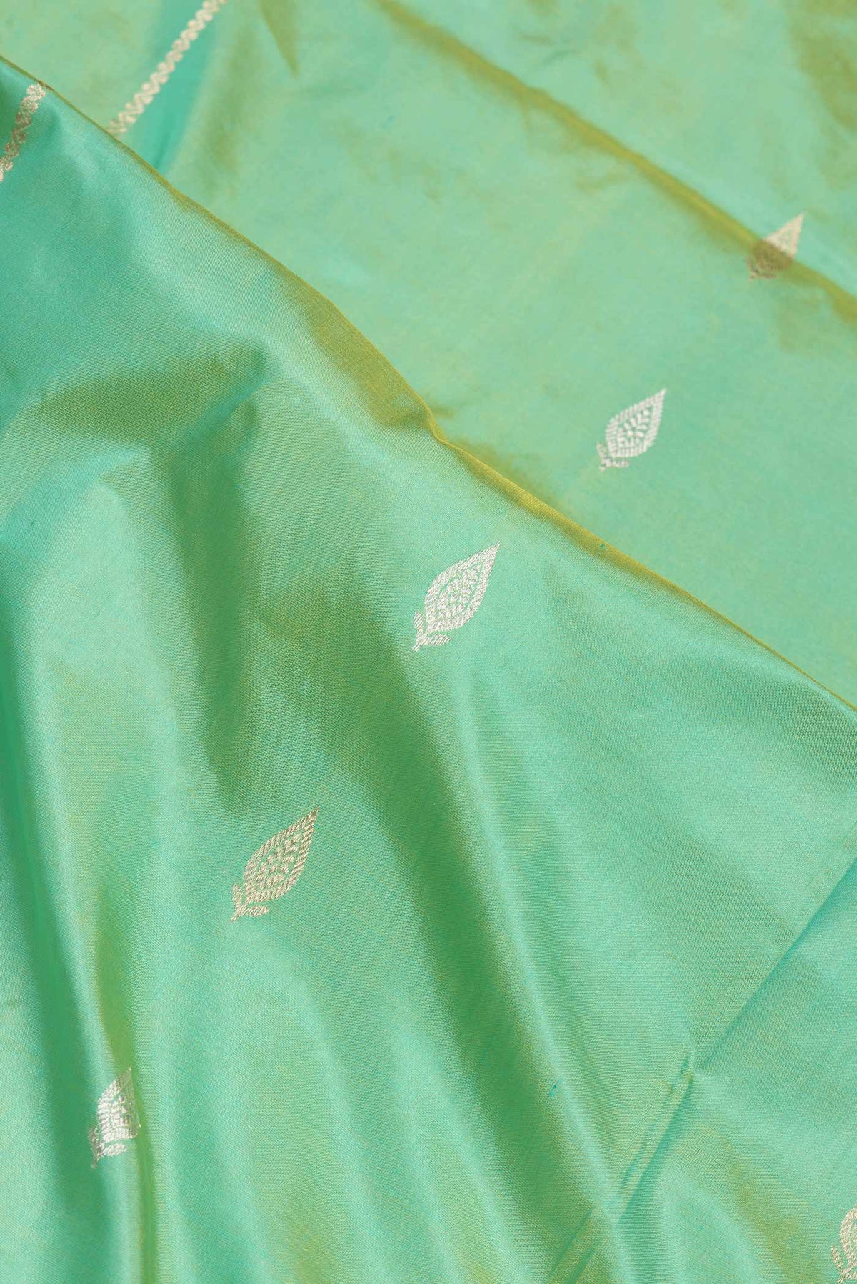 Close up of Green Dual Tone Banarasi Silk Saree with Zari Butta on the body and Thread Border.  displaying folds
