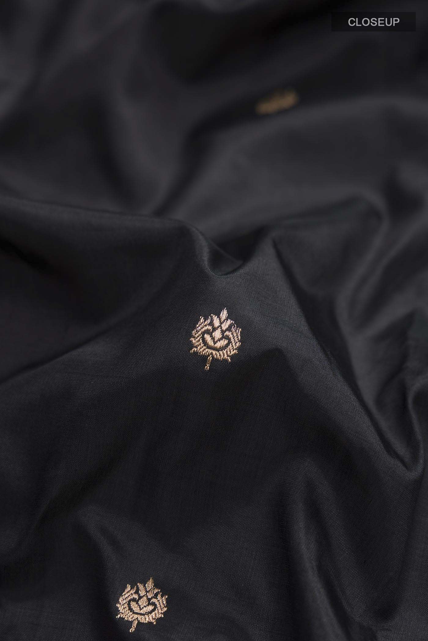 Close up of Black Banarasi Katan Silk Saree with Zari Butta on the body and Zari Border displaying folds