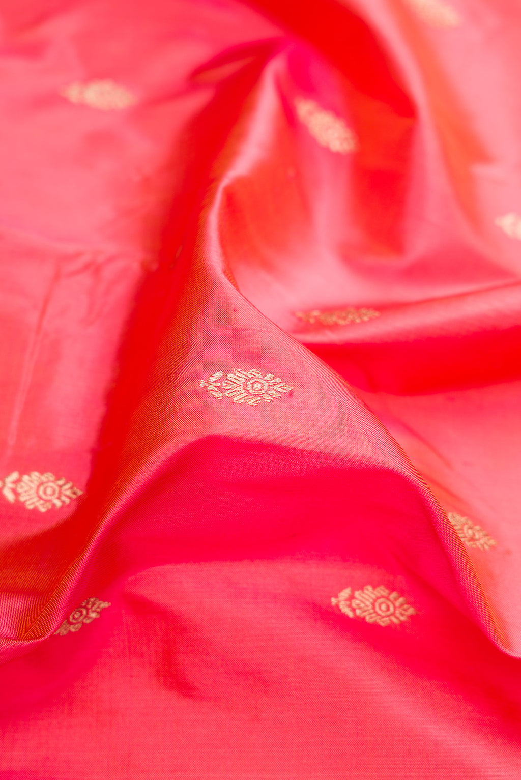 Close up of Coral Banarasi Katan Silk Saree with Zari Butta on the body and Fancy Border.  displaying folds