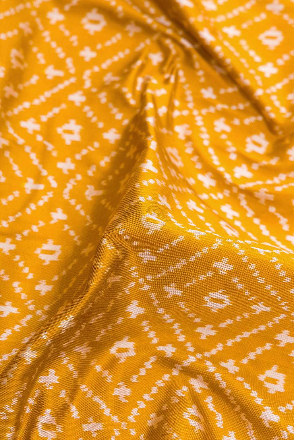 Close up of Mustard Dual Tone Double Ikat Nine Yards Saree with Ikat Print on the body and Zari Border.  displaying folds